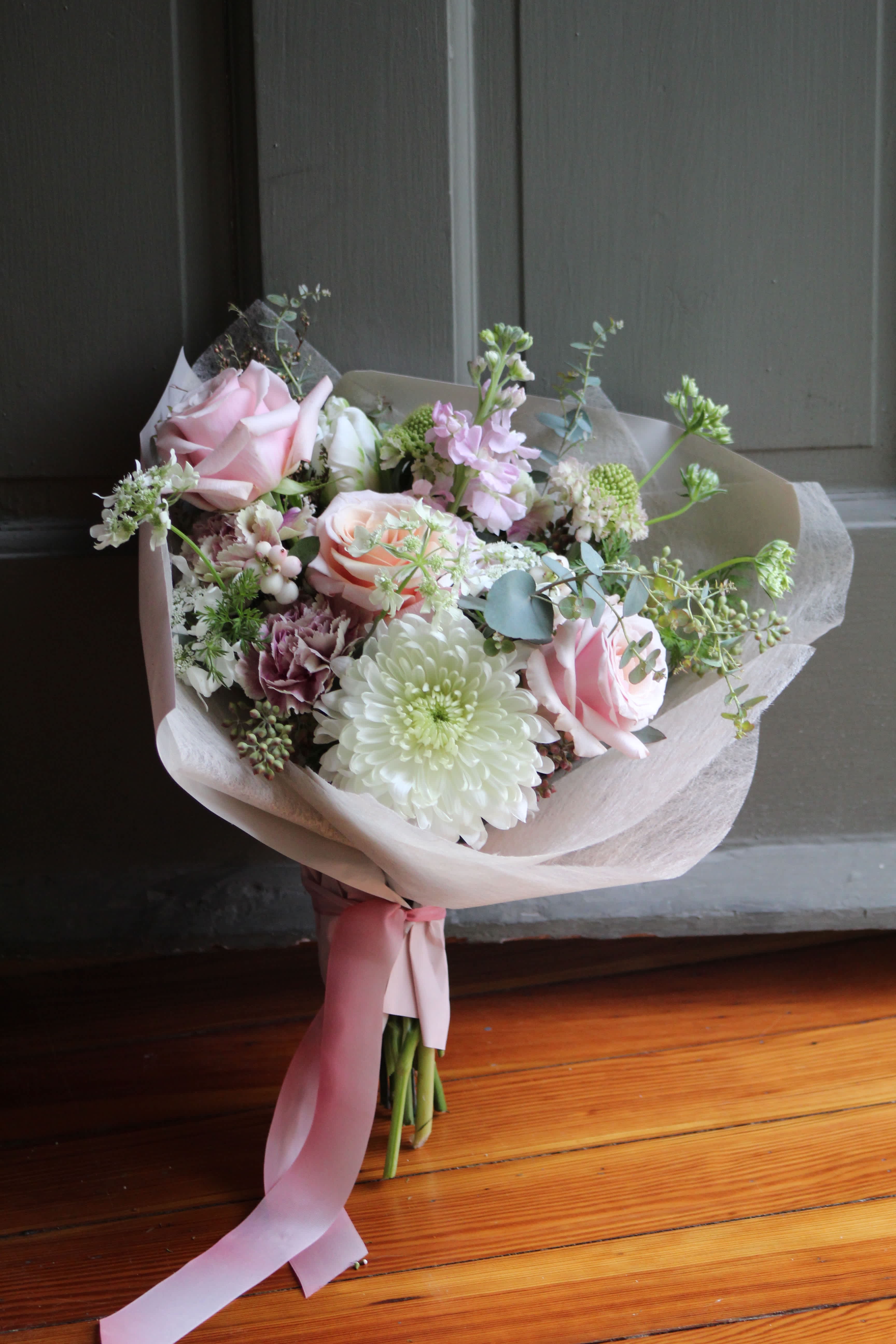 Bouquet of pink roses and white chrysanthemums wrapped in pale paper