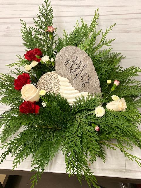 Sympathy floral arrangement with red and white flowers around a memorial stone