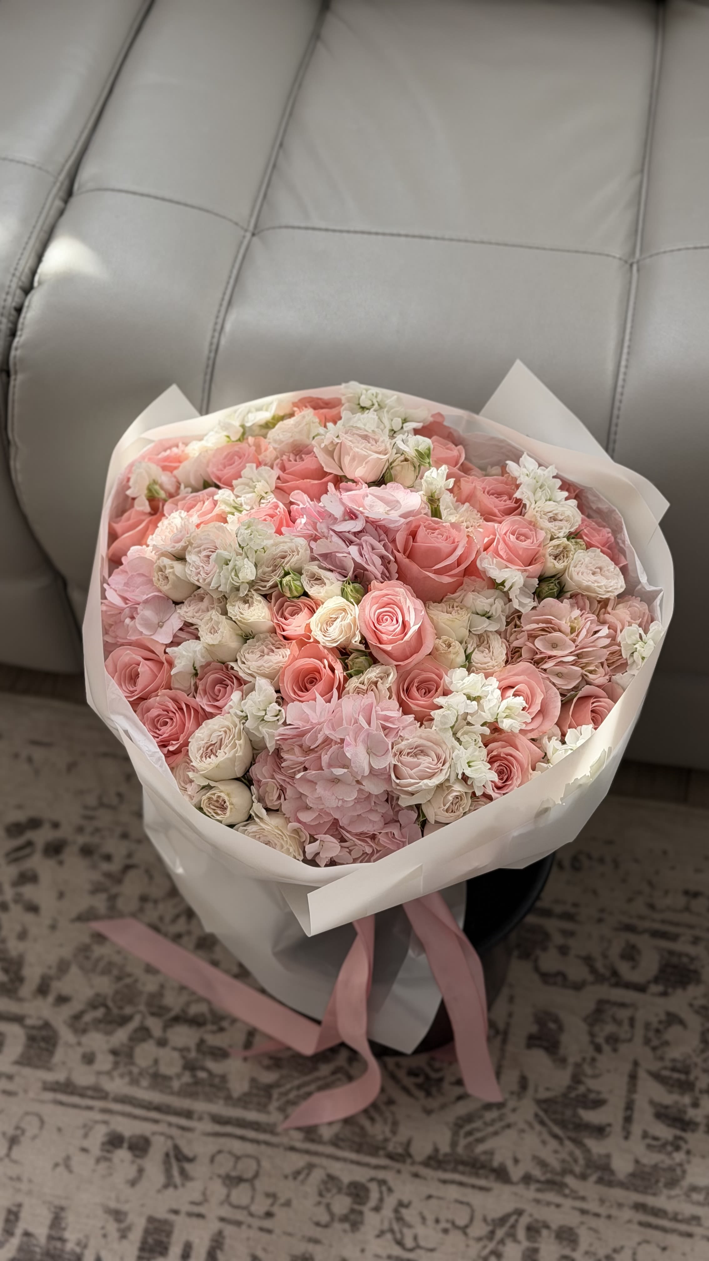 Blush Garden Symphony - An abundant, garden-style bouquet designed to feel soft, romantic, and effortlessly luxurious. Blush Garden Symphony features a delicate blend of premium roses, spray roses, hydrangea, and stock in a harmonious palette of blush pink, soft coral, and creamy ivory.