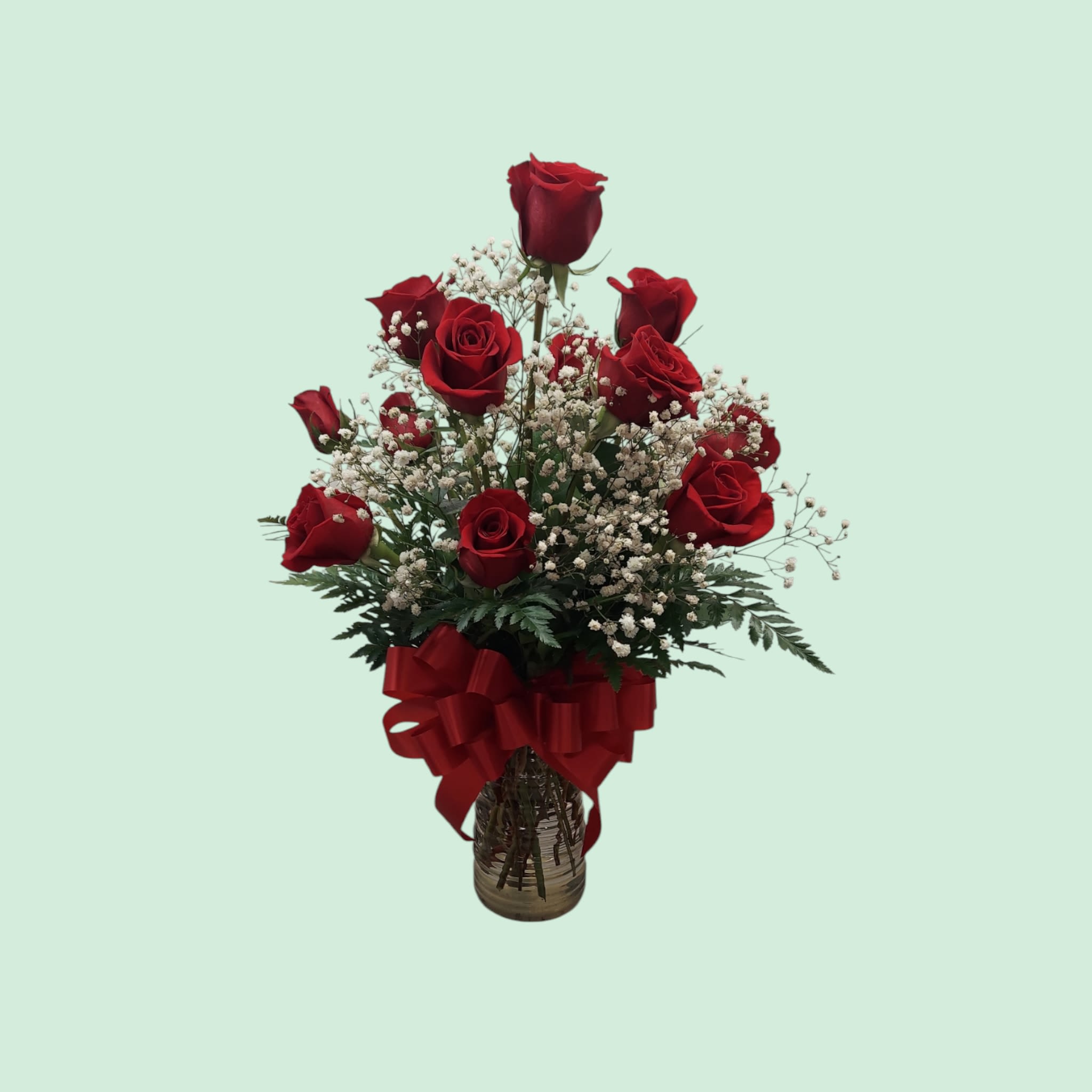 Red roses in a glass vase with baby's breath and a red ribbon