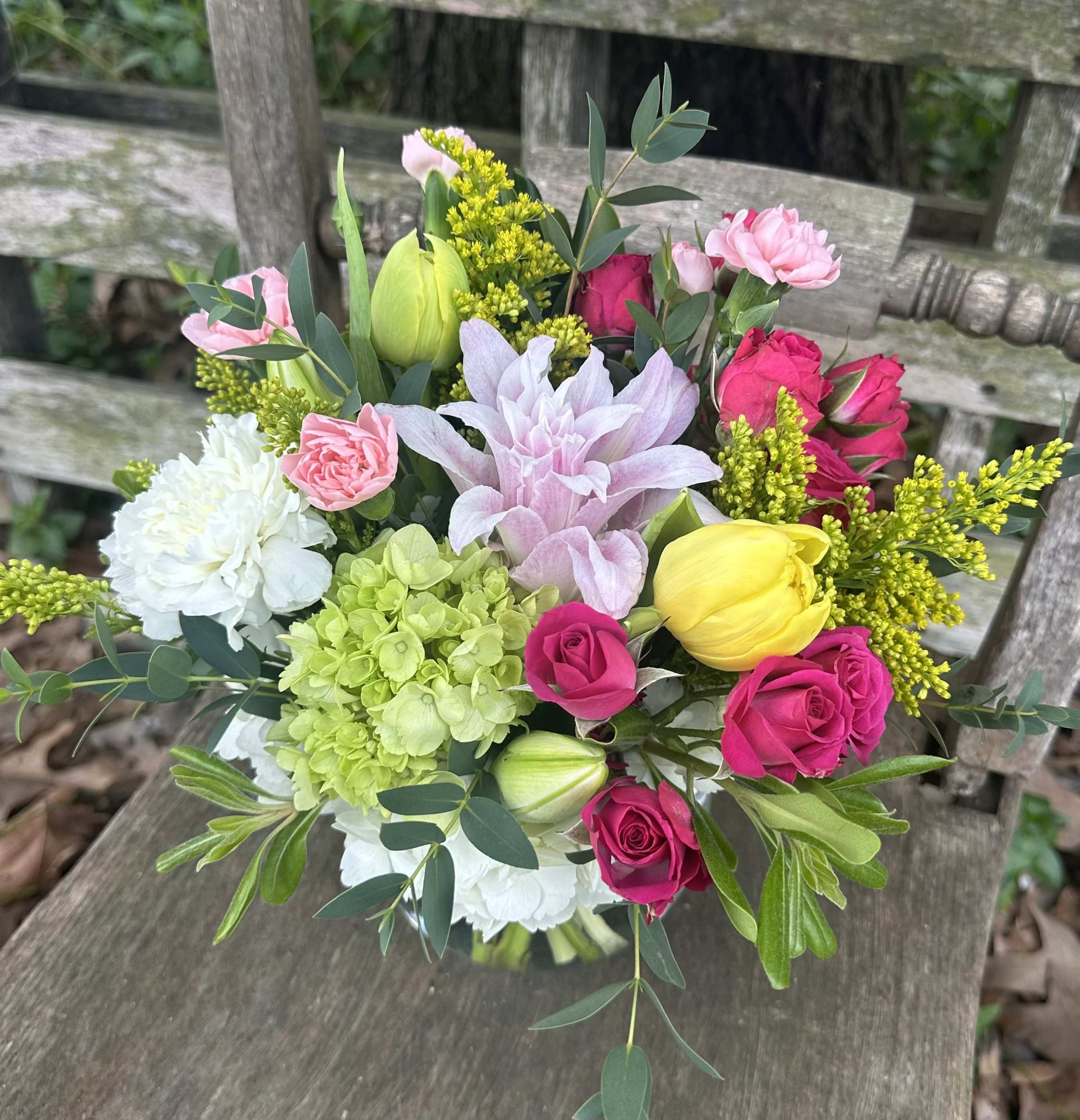 In Bloom - A sweet compact style arrangement filled with soft yellows, greens, and pinks with a touch of hot pink and white. Filled with hydrangeas, carnations, spray roses, and more, this arrangement is sure to make a loved one's day special.