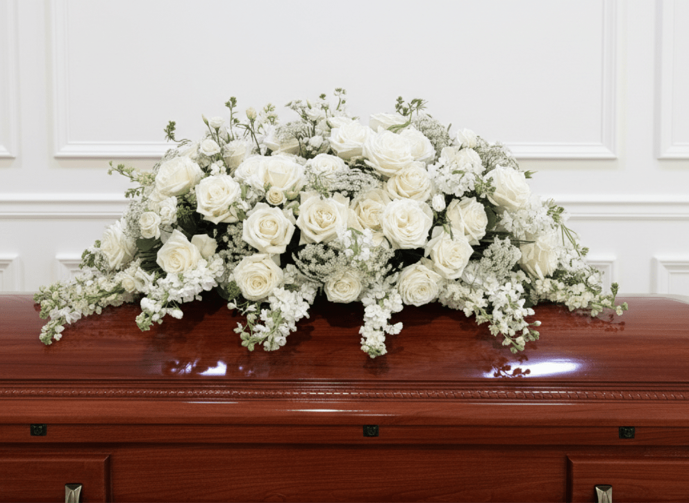 White Casket Cover - Large all-white casket spray of white roses and delicate filler flowers, draping softly across casket