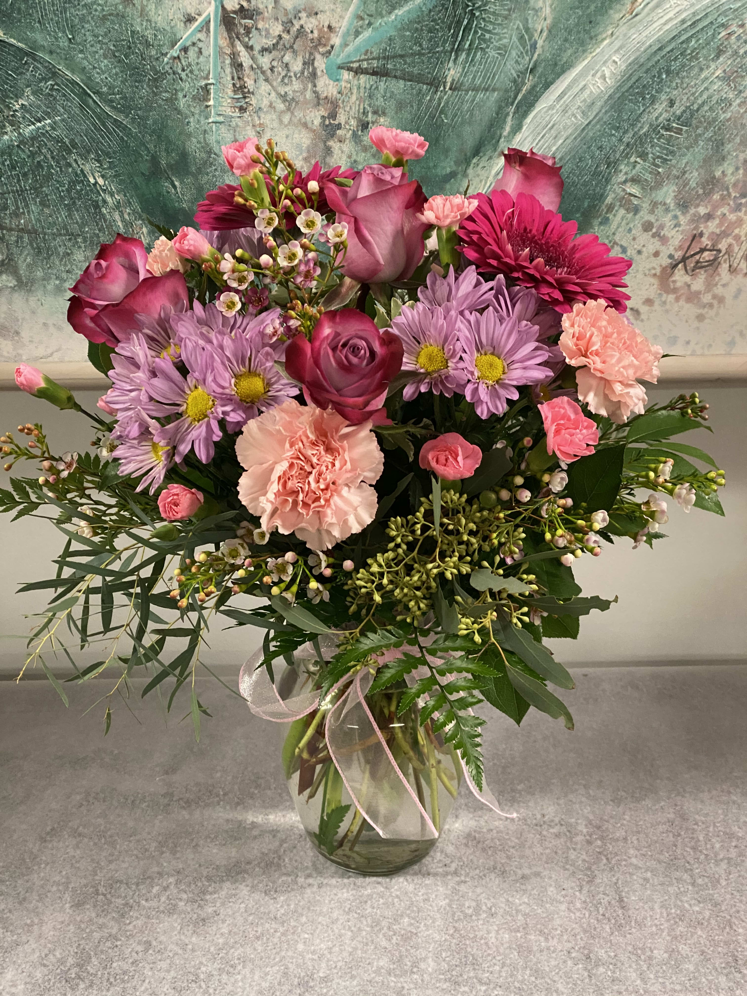 Pink and lavender mixed bouquet in a clear glass vase with a ribbon.