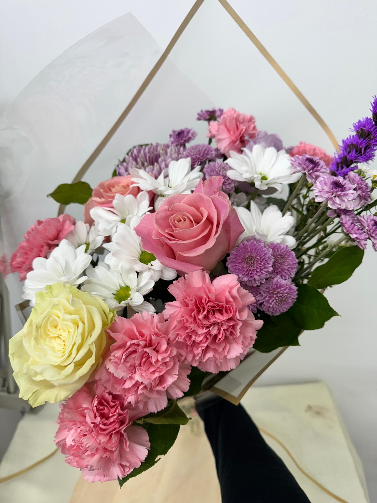 Bouquet of pink and white flowers with purple accents in clear wrap