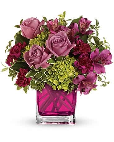 Pink roses and magenta flowers arranged in a square glass vase