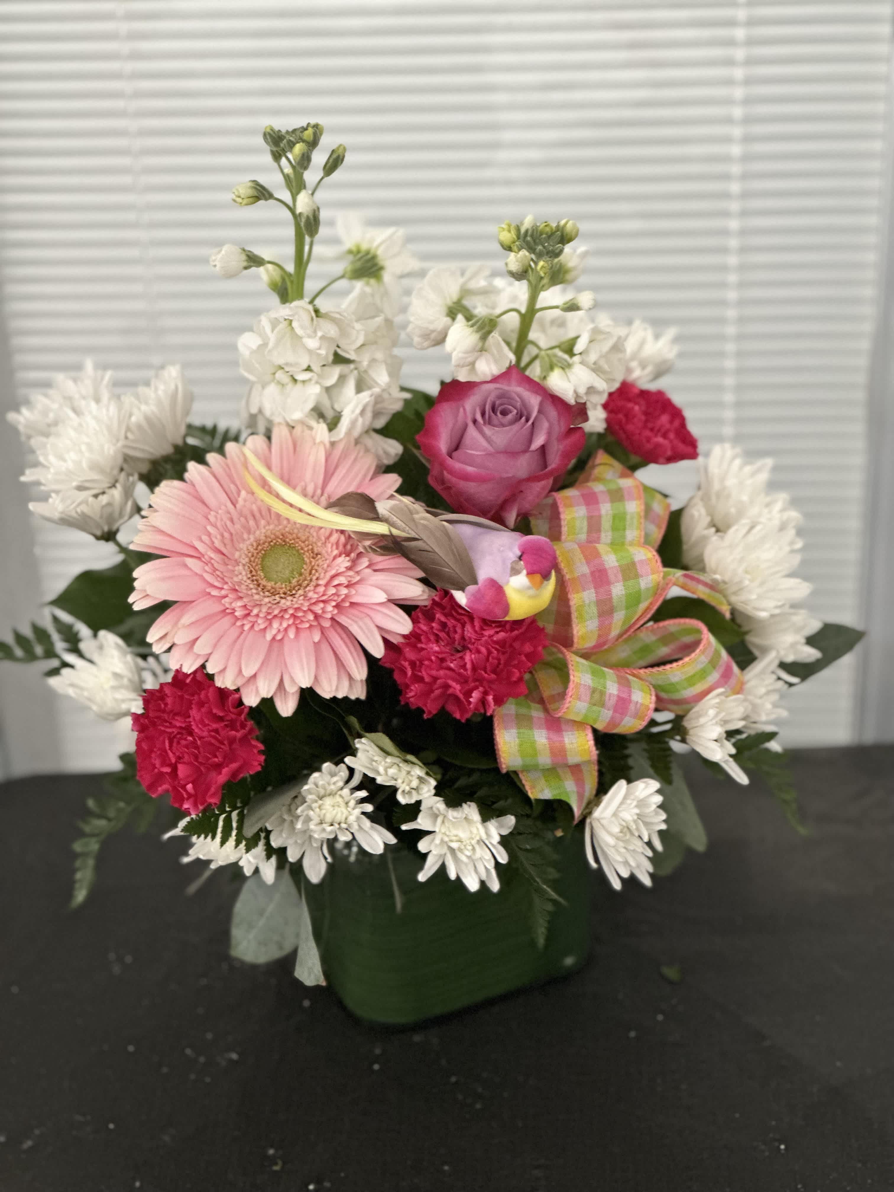 Pink gerbera and rose bouquet in a green vase with a plaid ribbon