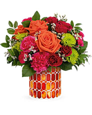 Mixed bouquet of orange, red, and pink flowers in a patterned vase