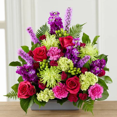 Warm Embrace Flower   -  Pet Friendly? No This arrangement contains Mums, which are part of the chrysanthemum family and can be toxic to household pets if ingested. Keep this display on a high counter or shelf to ensure it stays out of reach of curious cats or dogs.    Human Allergy Note This arrangement contains Mums and Liatris, which are known to carry more pollen than other varieties and may trigger sensitivities. We recommend placing the arrangement in a well-ventilated area rather than a small, enclosed bedside table.   Care &amp; Longevity To keep these blooms fresh, add a small amount of water to the container daily to keep the floral foam saturated. Avoid placing the arrangement in direct sunlight, near heating vents, or in drafty areas. Gently remove any fading petals or leaves to keep the water clean and the arrangement looking its best.   Best Occasions &amp; Situations  Birthday – vibrant and festive without being loud  Just because – sends warmth any day ‍ Graduation flower – proud, elevated look  Get well – uplifting tones for recovery  Mother's Day – rich, heartfelt palette  Romance/anniversary – roses + deep tones set the mood  Retirement flower – distinguished and cheerful  Why Customers Love It High-contrast palette that instantly grabs attention. Modern container that fits perfectly on narrow mantels or desks. Long-lasting variety featuring sturdy blooms like carnations and mums. Full-circle design that looks beautiful from every angle.