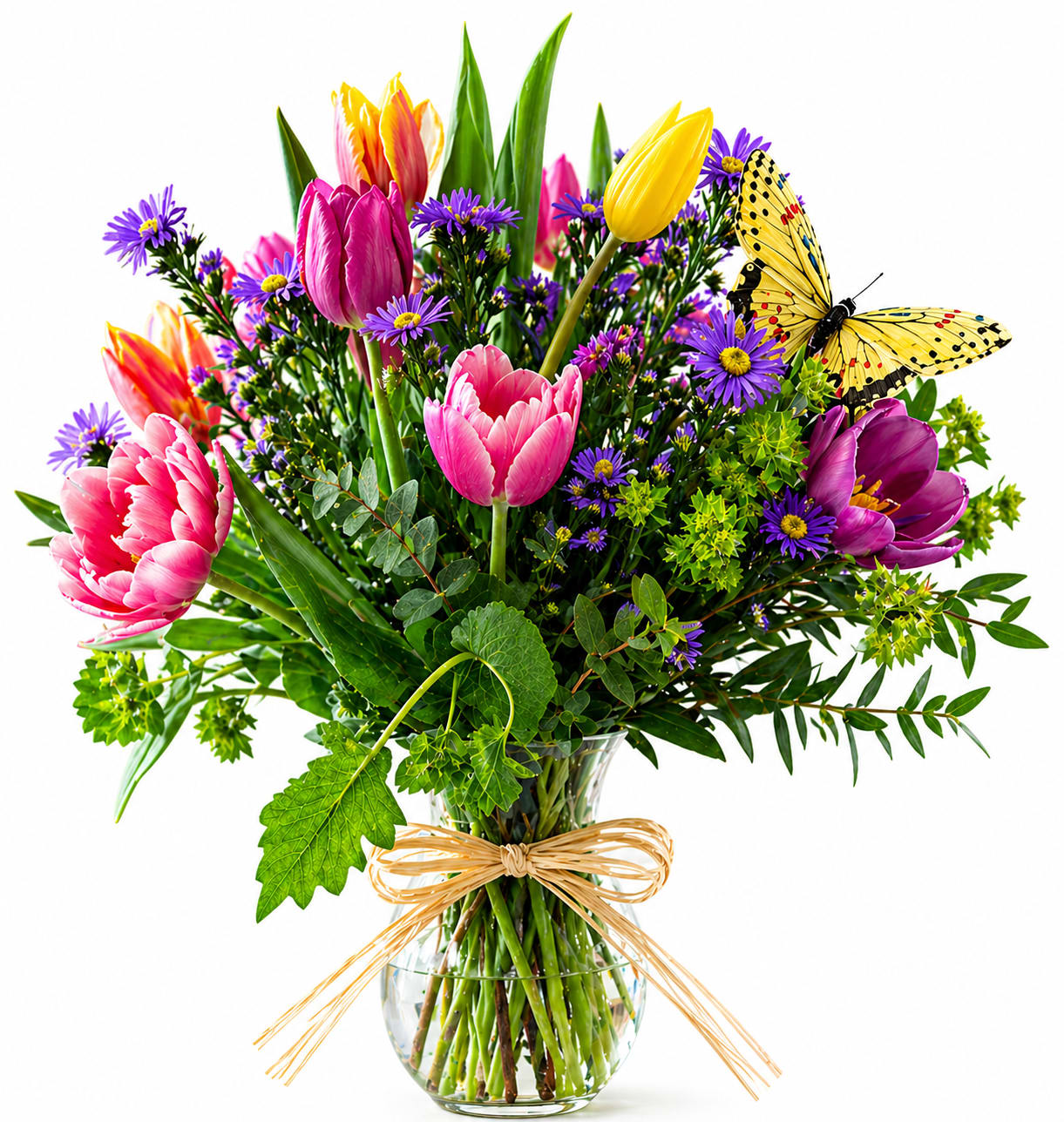 A Simple I Love You - A bright cluster of tulips in pink, purple, yellow and coral greets the room with cheerful energy-perfect as a birthday bouquet, Mother's Day gift, or a spontaneous "I love you" surprise. The lively mix of tulips and small purple aster-like blooms reads fresh and garden-like, so the person you're thinking of will feel noticed and genuinely celebrated the moment they see it.  Gathered in a clear round glass vase and finished with a pale ribbon or rustic raffia bow, the arrangement has a polished yet hand-tied look that suits casual desks, kitchen tables, or bedside tables. A decorative butterfly ornament perches on the side for a playful, springtime touch. This size is ideal for everyday gifting and seasonal celebrations; keep blooms in fresh water and away from direct heat to extend their life.