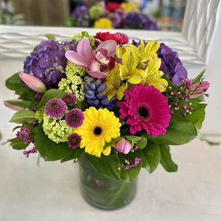 Spring Blossom - A vibrant blend of fresh spring blooms arranged into a glass vase with mixed greenery.