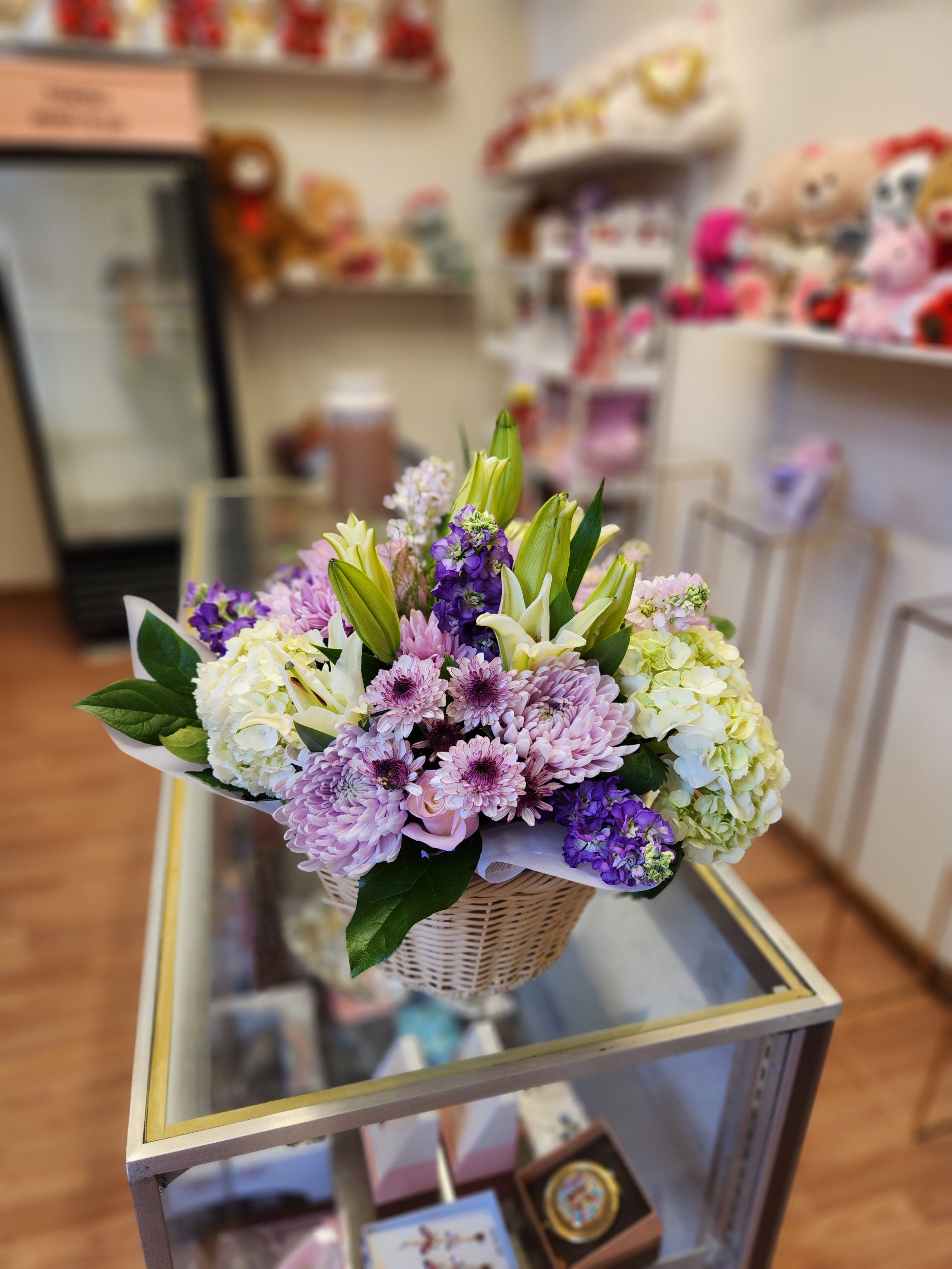 Basket arrangement of lilies, chrysanthemums, and hydrangeas in purple and white