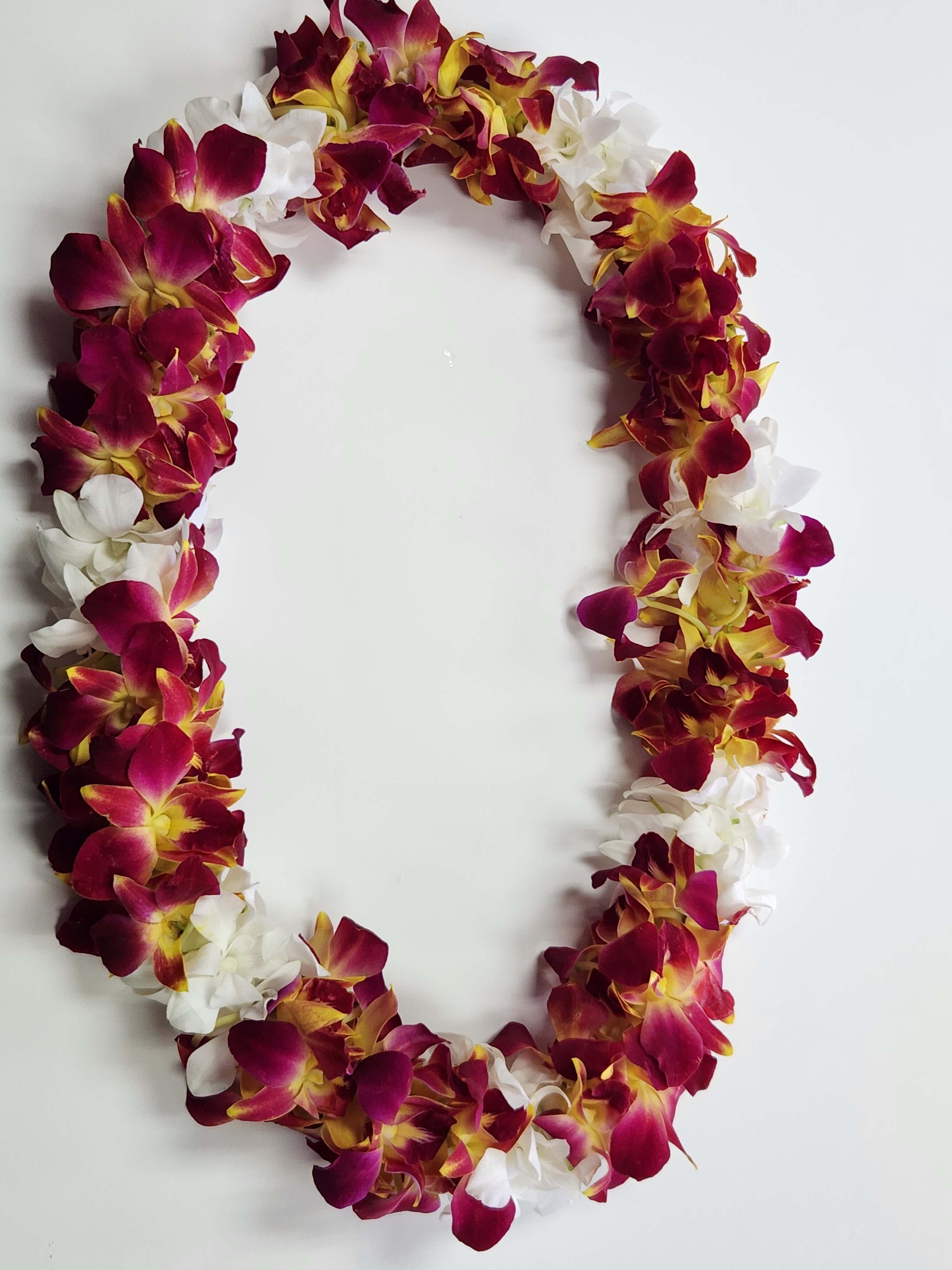 Purple, yellow, and white orchid lei arranged in an oval on a white background.