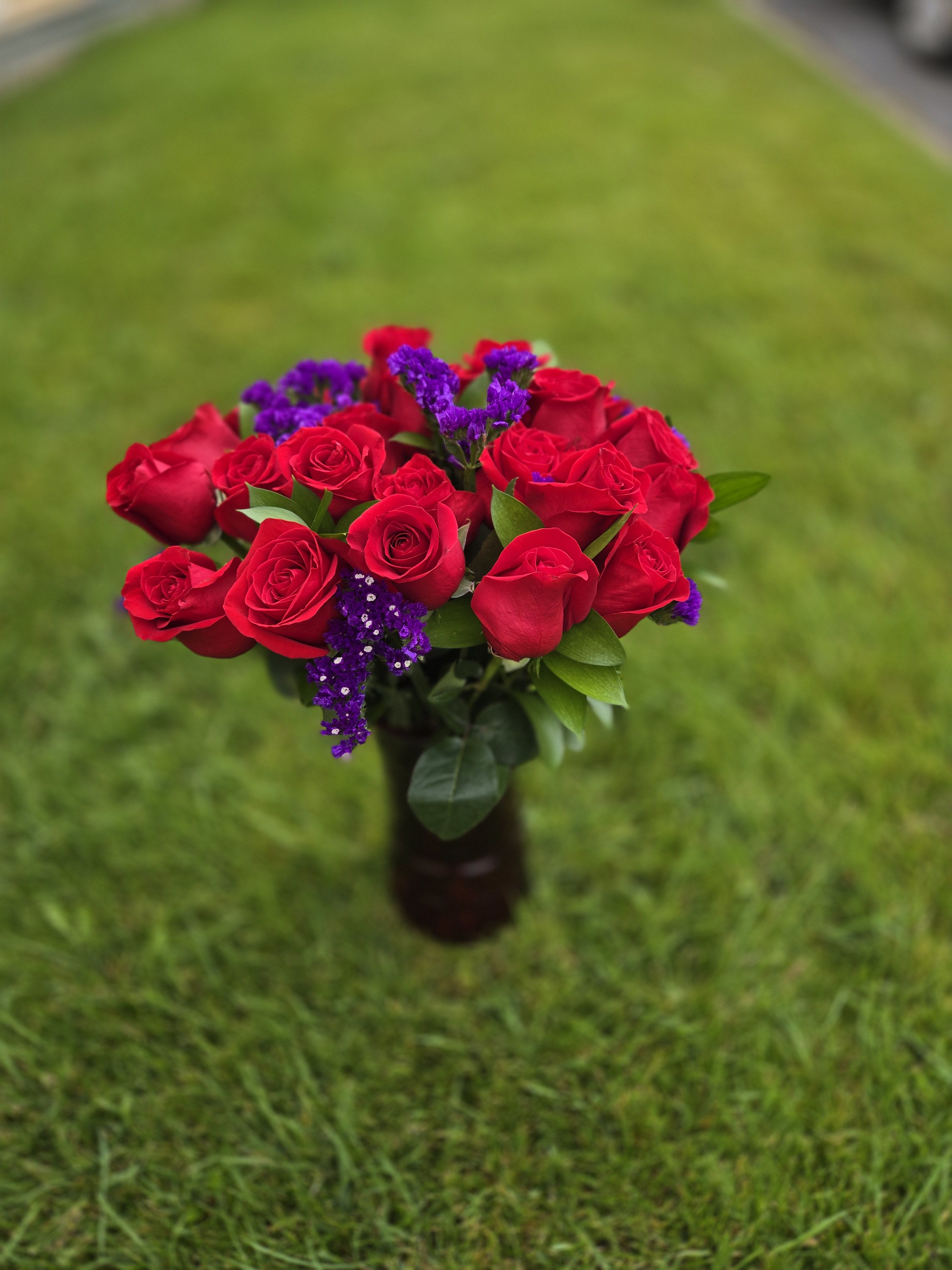Bouquet of red roses with purple filler flowers in a vase
