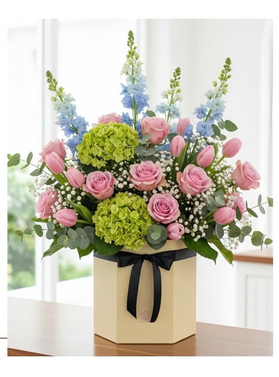 Pastel Garden round box  - Revel in the freshness of our floral arrangement featuring green hydrangeas, pink tulips, and Pink Roses, beautifully accented with blue delphinium , green fillers. Presented in a round box, this ensemble exudes natural beauty and charm. Order now to brighten your space or to delight someone special with this refreshing floral display!