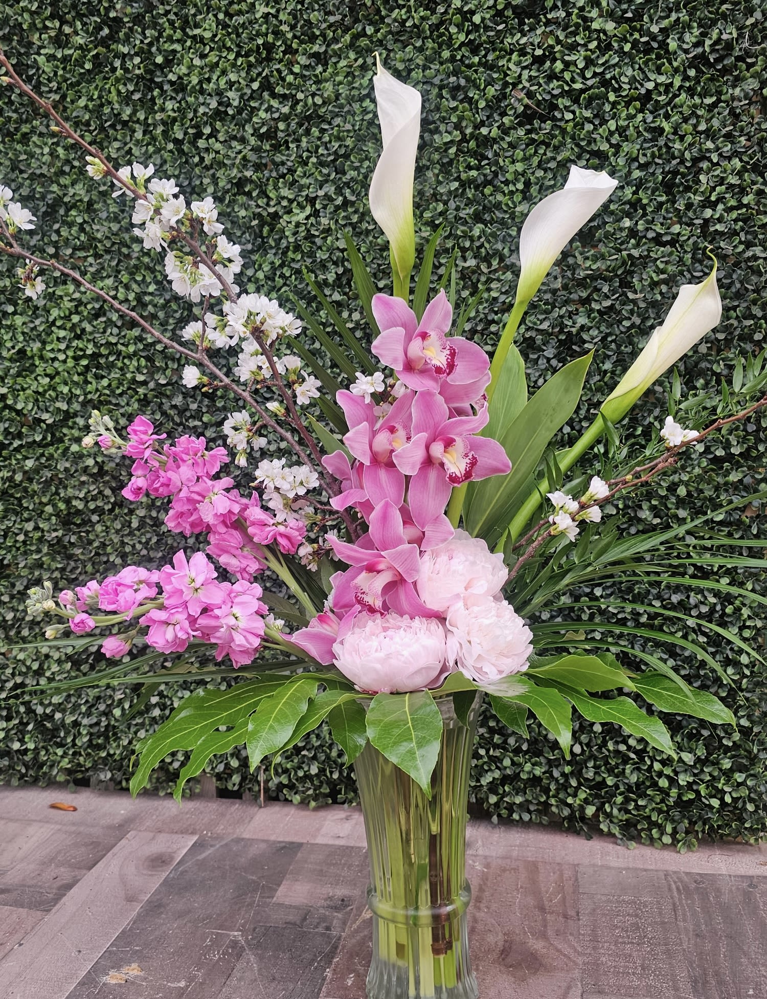 Tall pink orchid arrangement with white calla lilies in a glass vase