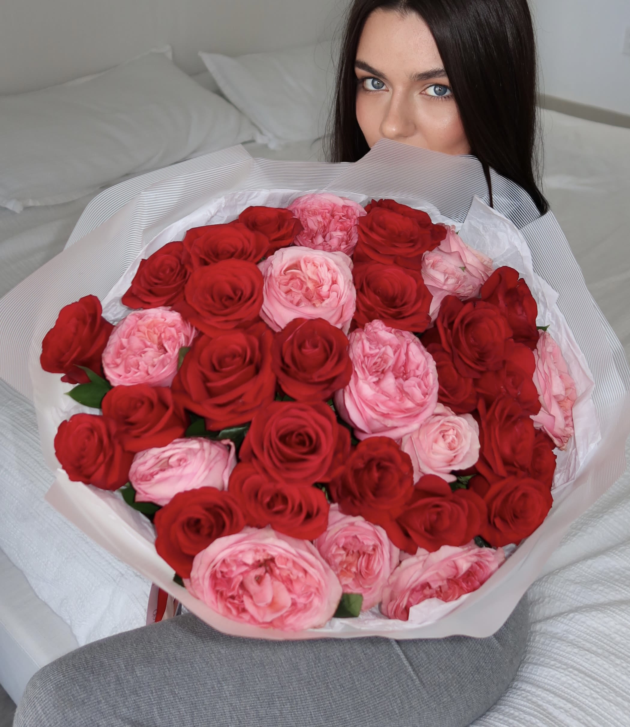 Woman holding a large bouquet of red and pink roses