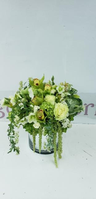 Green and white floral arrangement in a round container