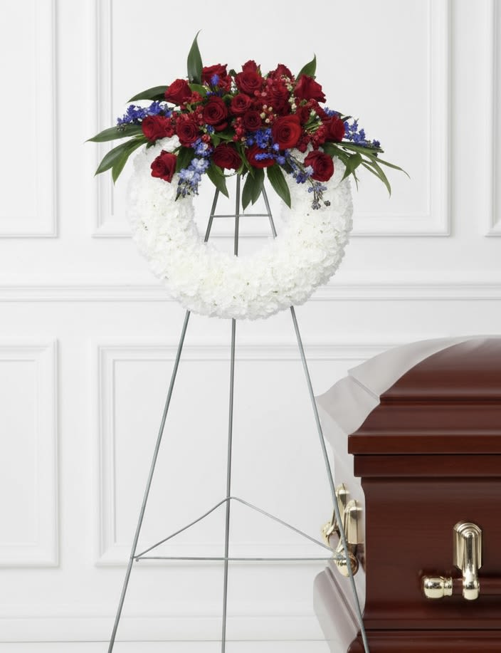 White and Red Open Wreath - Standing open wreath on an easel with white blooms, top cluster of deep red roses and blue accents.