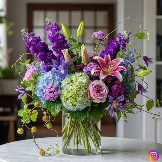 Royalty - A bold, gorgeous composition in an elevated palette of pinks, purple and sky blues. Premium blooms—think velvety garden roses, delicate lilies, and airy iris—are artfully gathered into a lush silhouette. The result is an indulgent, couture‑style arrangement that feels both graceful and exquisitely designed.