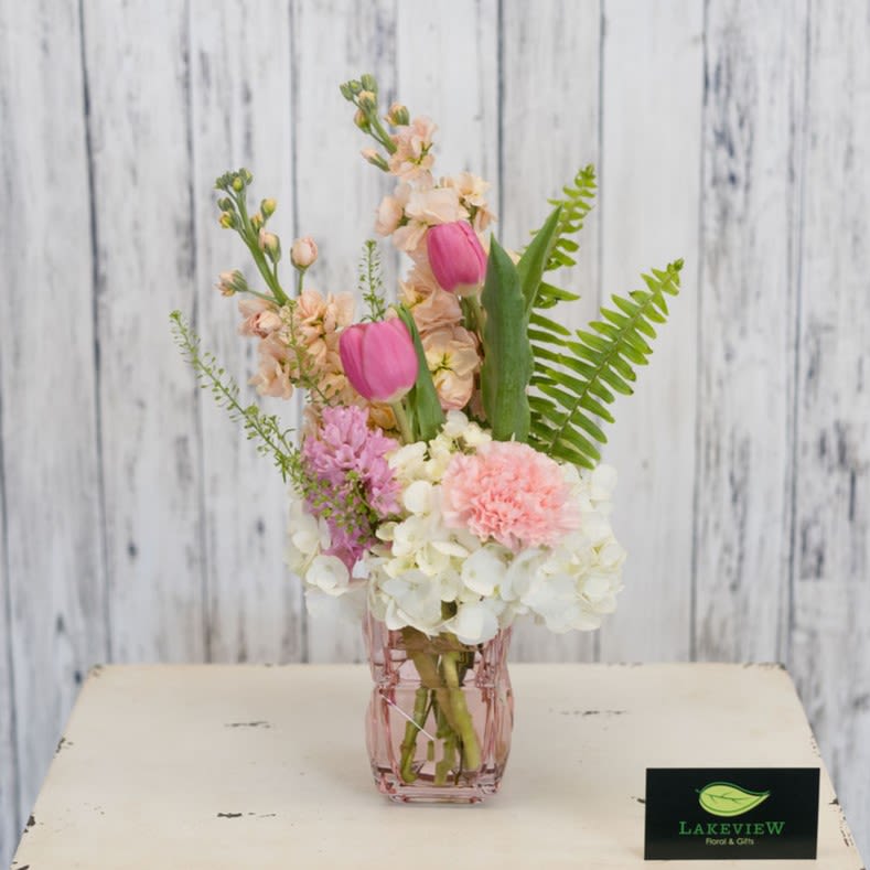 Delicate - Soft pastels and airy texture come together in this delicate arrangement, a charming flower assortment perfect for Mother's Day! The vertical, romantic design features pink tulips and pale peach stock alongside white hydrangeas and pink carnation blooms, all presented to make Mom feel gently celebrated.  Arranged in a small faceted pink glass vase, Delicate mixes carnations, hyacinth, tulips, stock, and hydrangea in shades of pink, peach, white, and fresh green-accented by bright fern fronds for contrast and movement. The look is fresh and feminine without feeling fussy; compact and gift-ready, it brings springtime scent and softness to a bedside table or kitchen counter.   Approx. 12"H x 8"W *This item is a Mother's Day Special and is available May 7-9th*