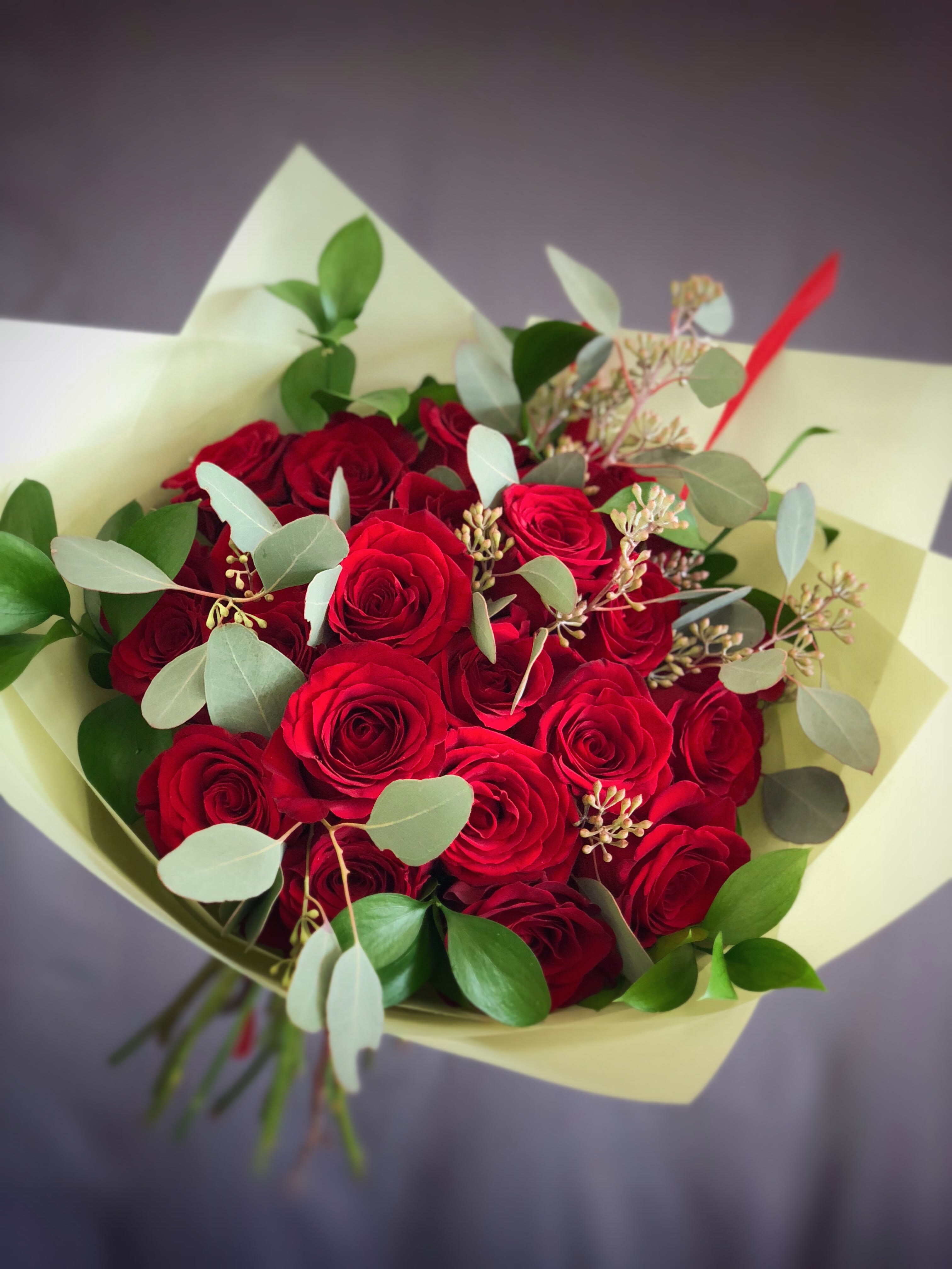 Bouquet of red roses with eucalyptus in pale wrapping