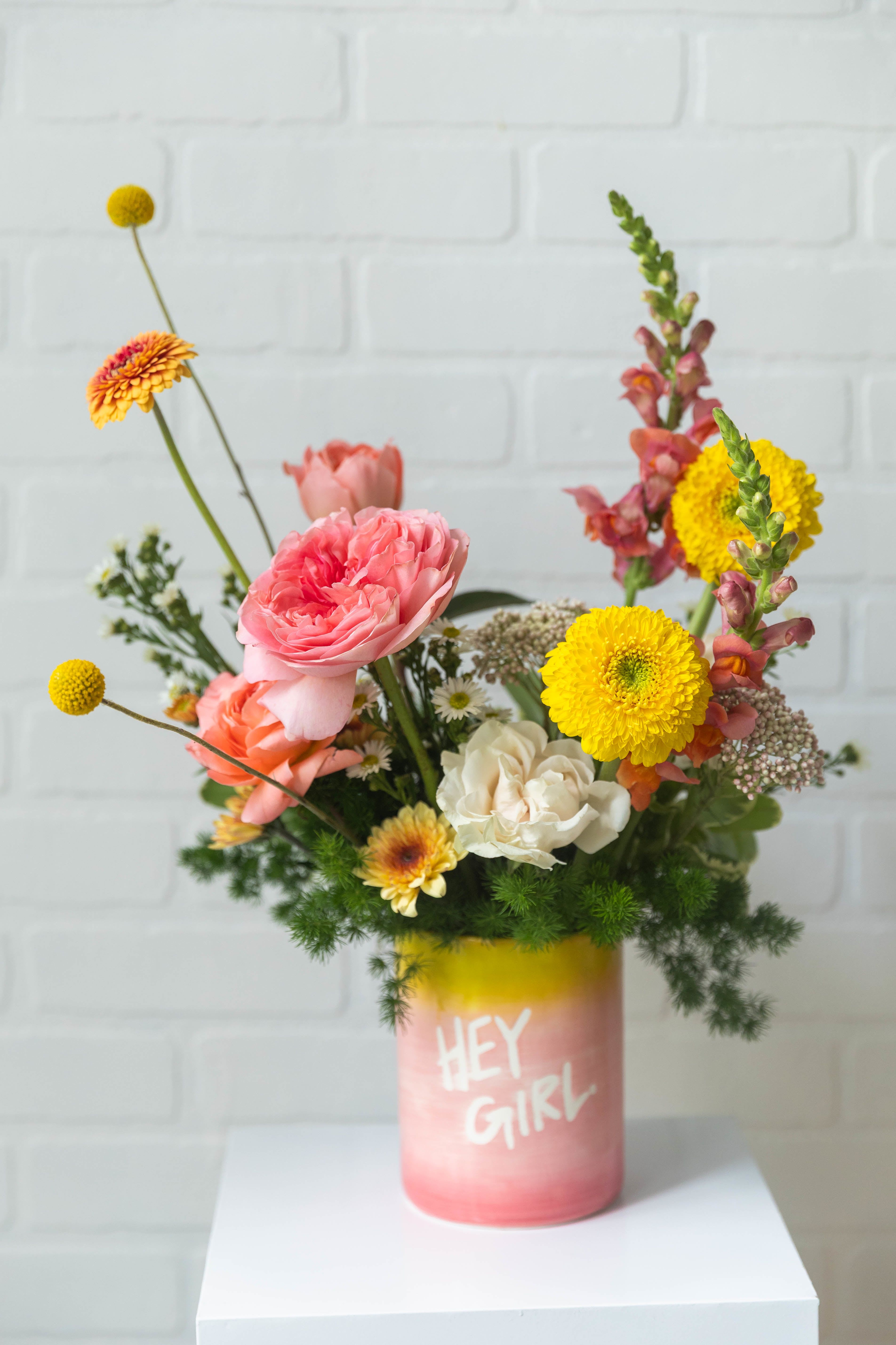 Hey Girl - Bright, playful, and full of personality—just like her. This cheerful arrangement features vibrant seasonal blooms in warm, happy tones, designed in a fun keepsake vessel that’s sure to make her smile.
