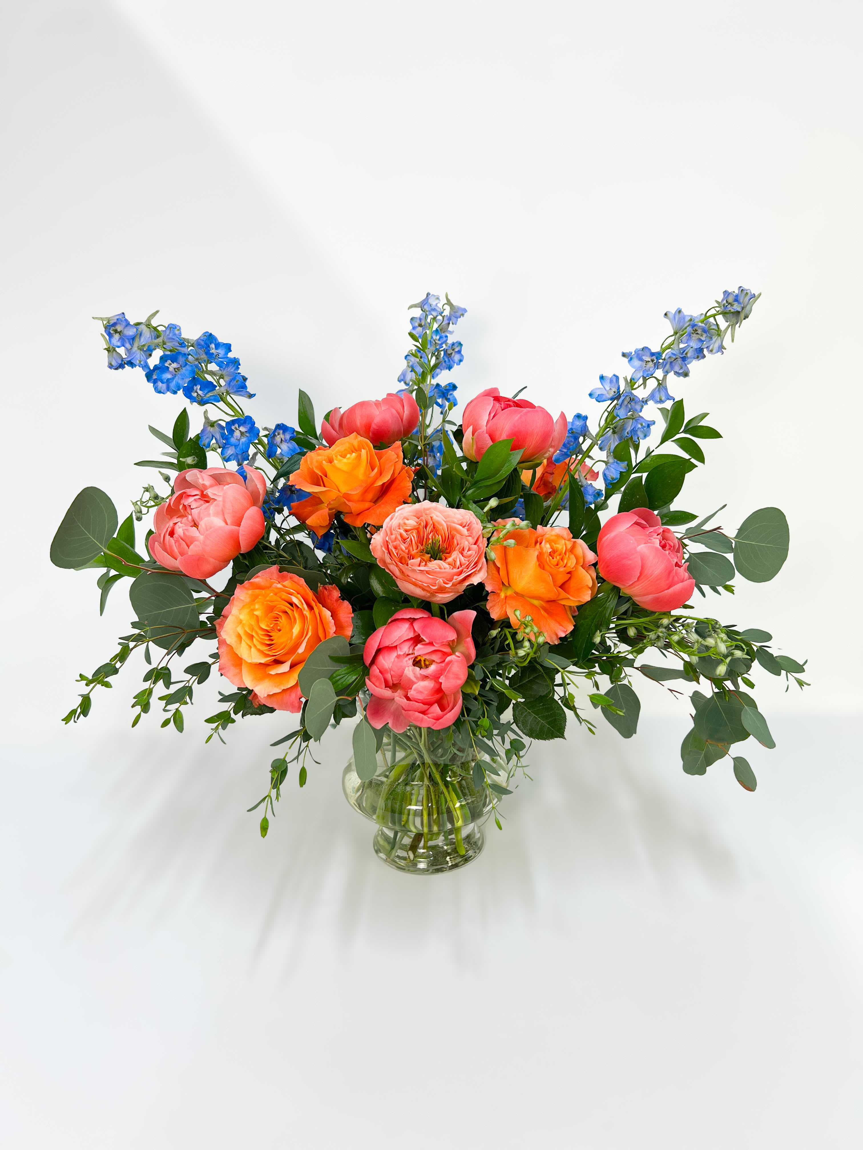 Bright mixed bouquet of pink and orange flowers in a clear glass vase