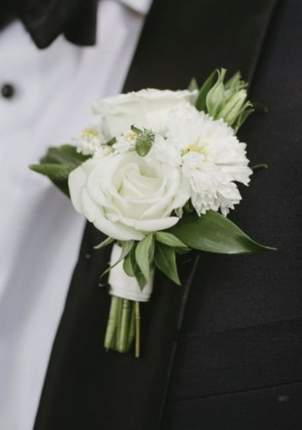 White rose and mum boutonniere pinned to a black tuxedo lapel