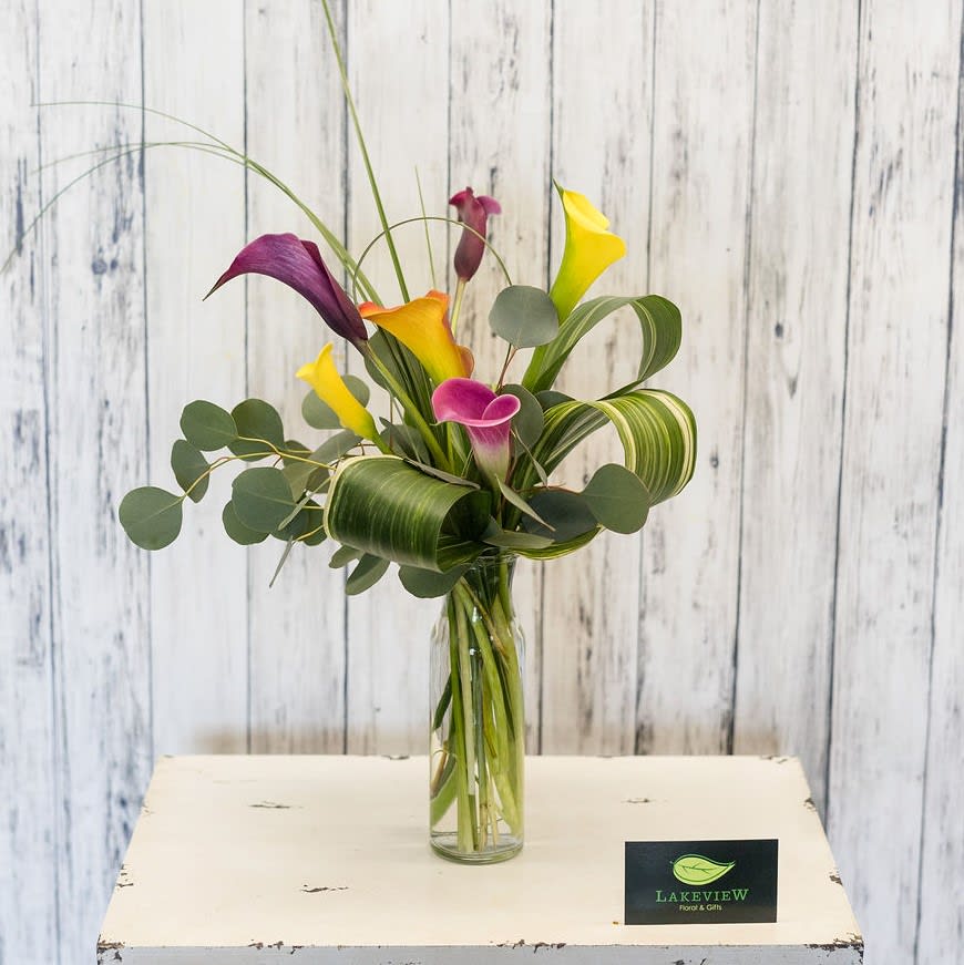 Tall bouquet of colorful calla lilies in a glass vase