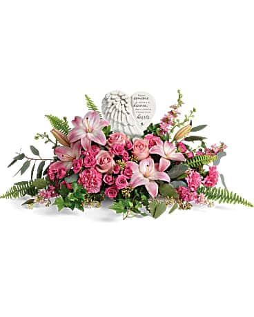 Pink lilies and roses arranged around a heart-shaped memorial plaque