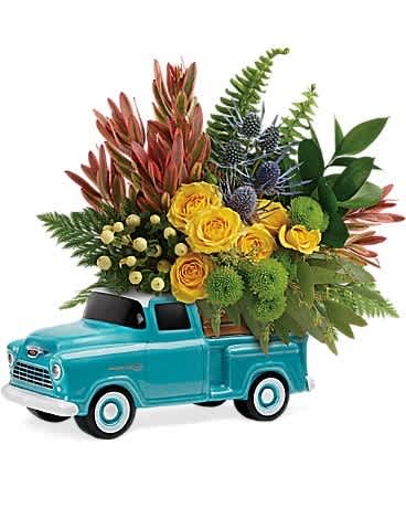 Yellow roses and mixed greenery arranged in a turquoise toy truck