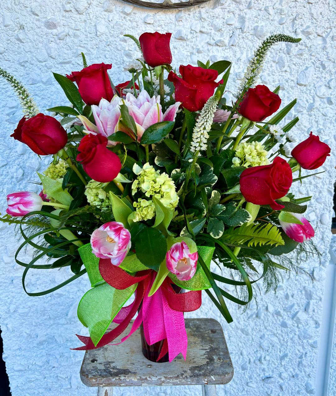 Bouquet of red roses and pink tulips in a glass vase