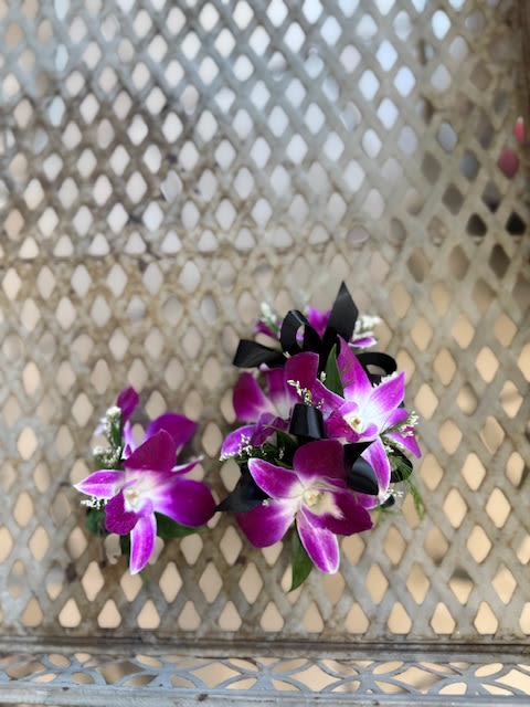 Two purple orchid corsages with black ribbon accents