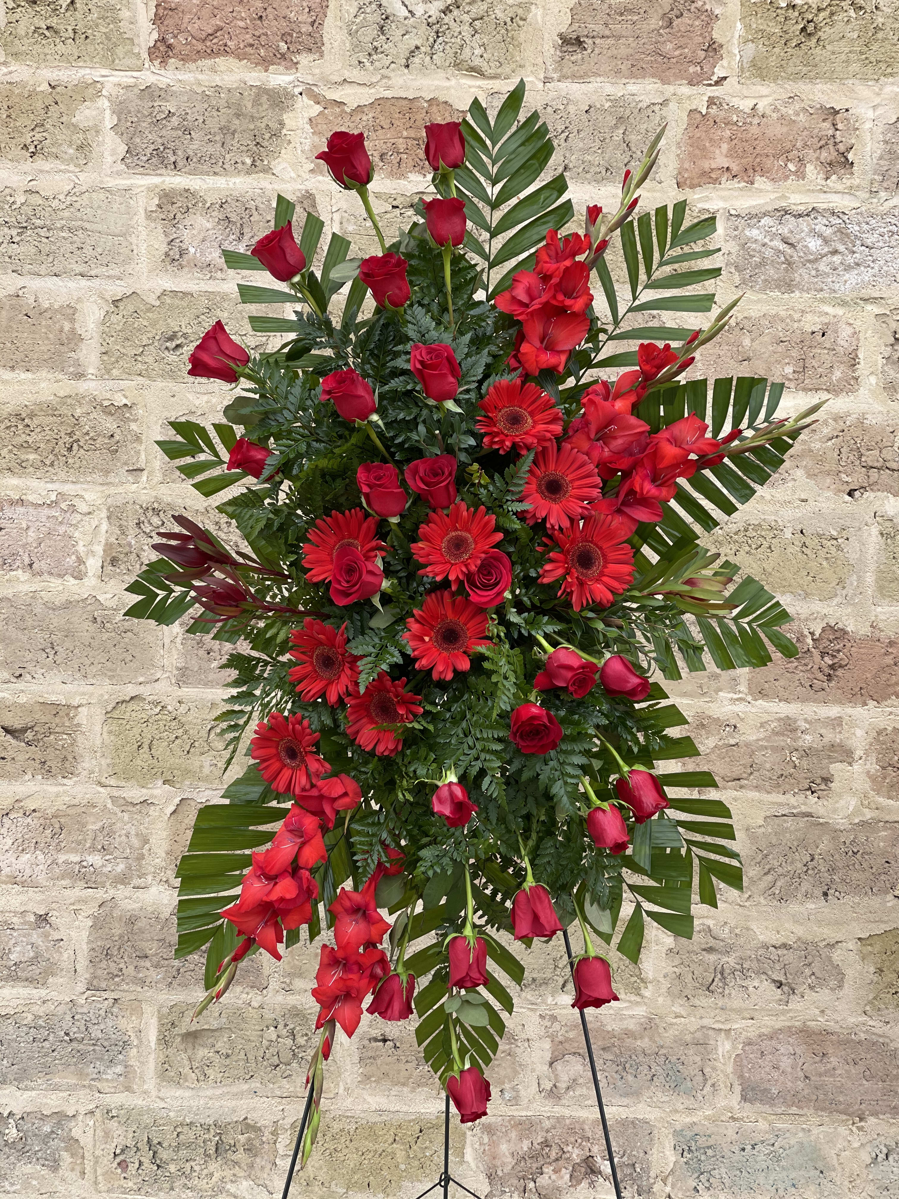 Red roses and gerbera daisies in a standing spray with greenery