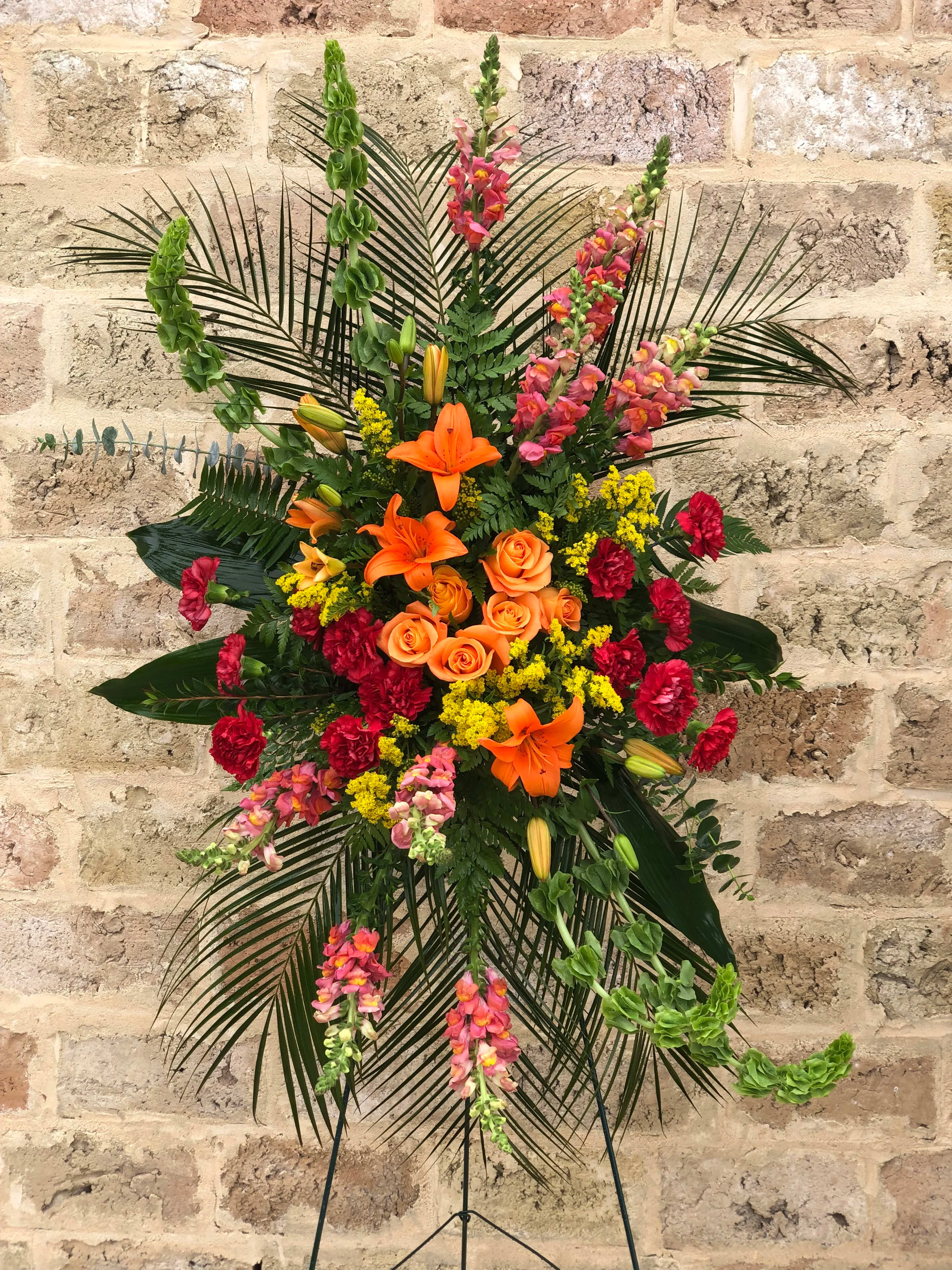 Tall floral standing spray with orange lilies, roses, and pink snapdragons
