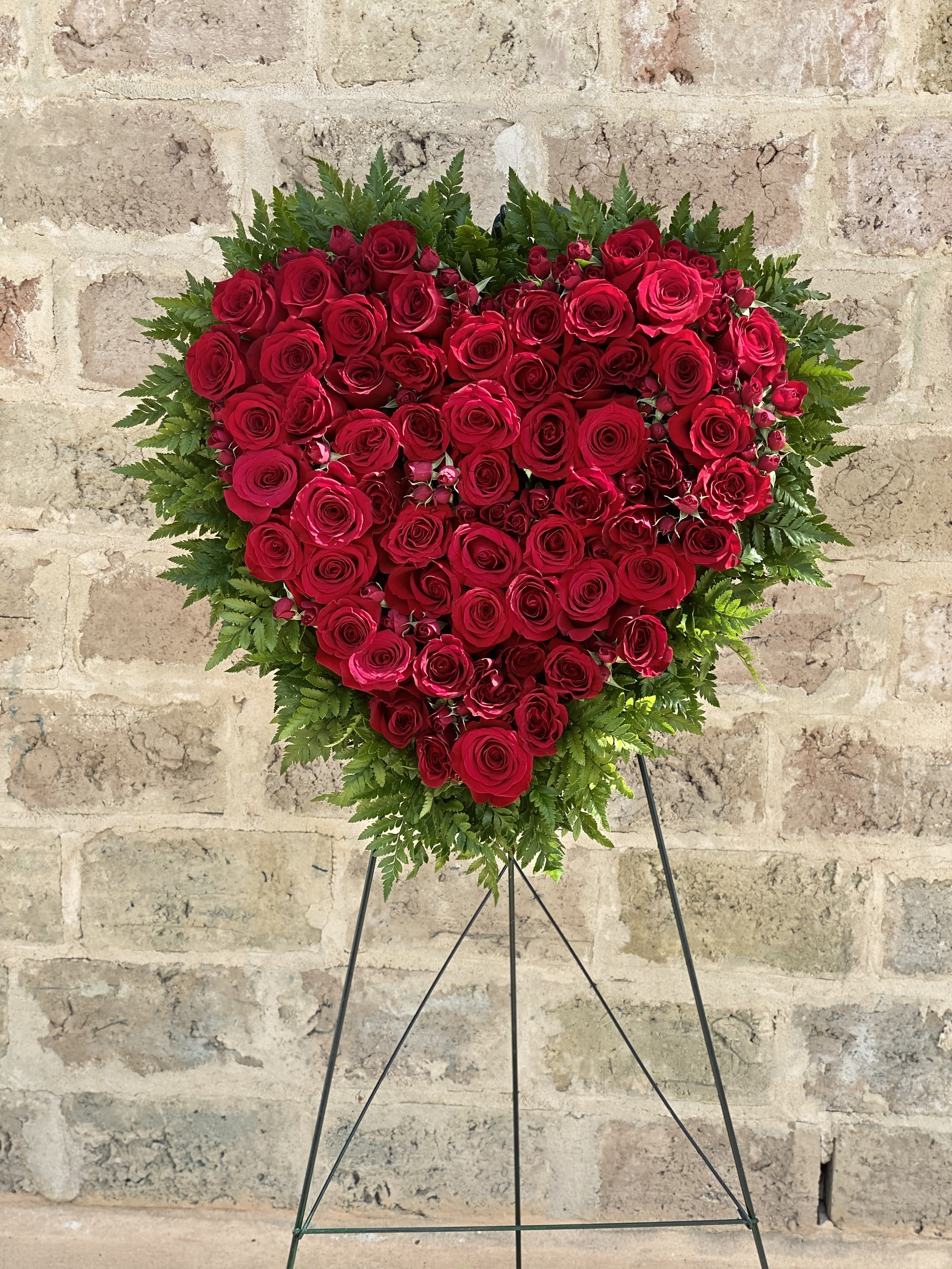Heart-shaped red rose arrangement on a stand