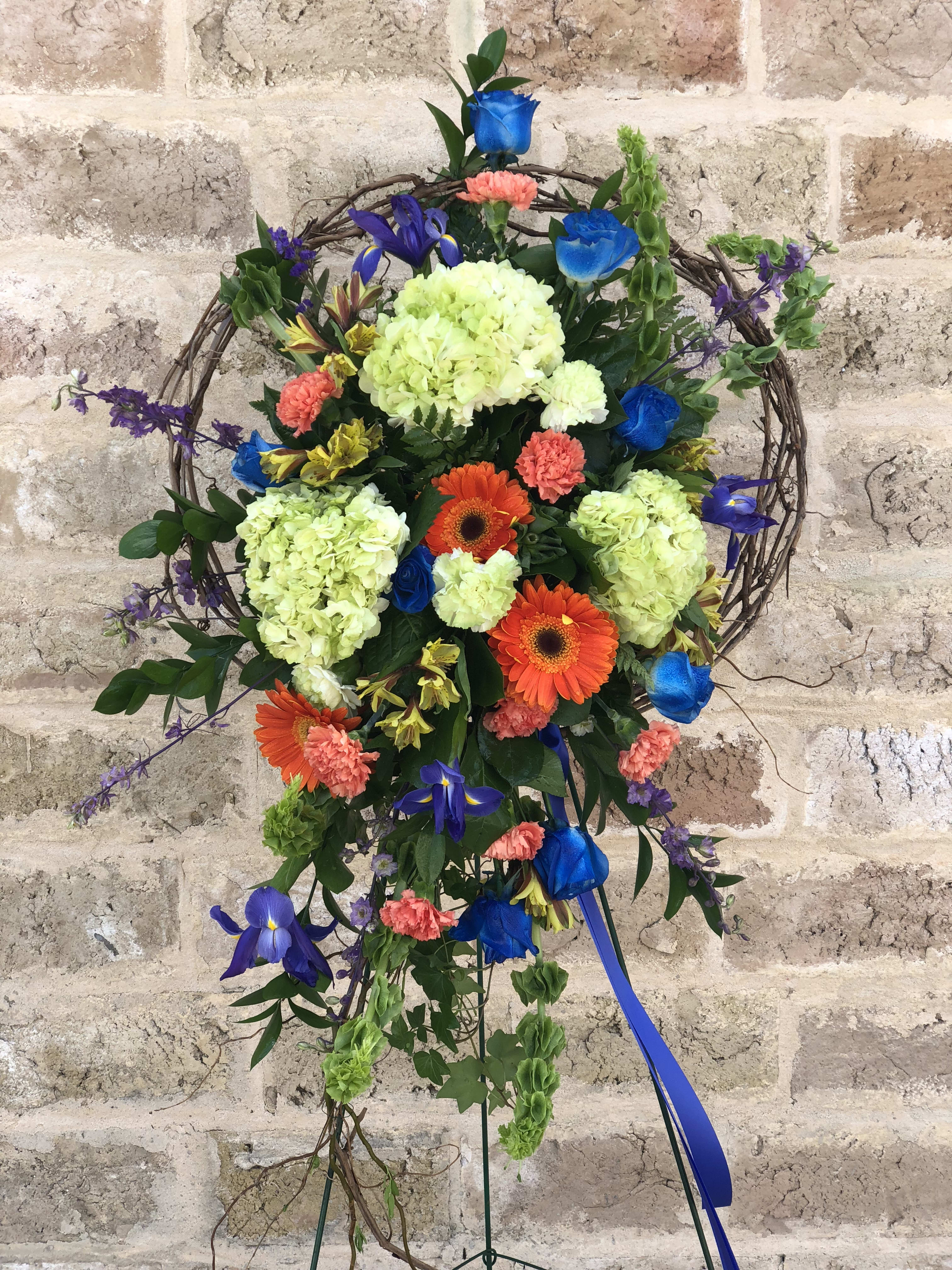 Colorful floral wreath on a stand with blue ribbon
