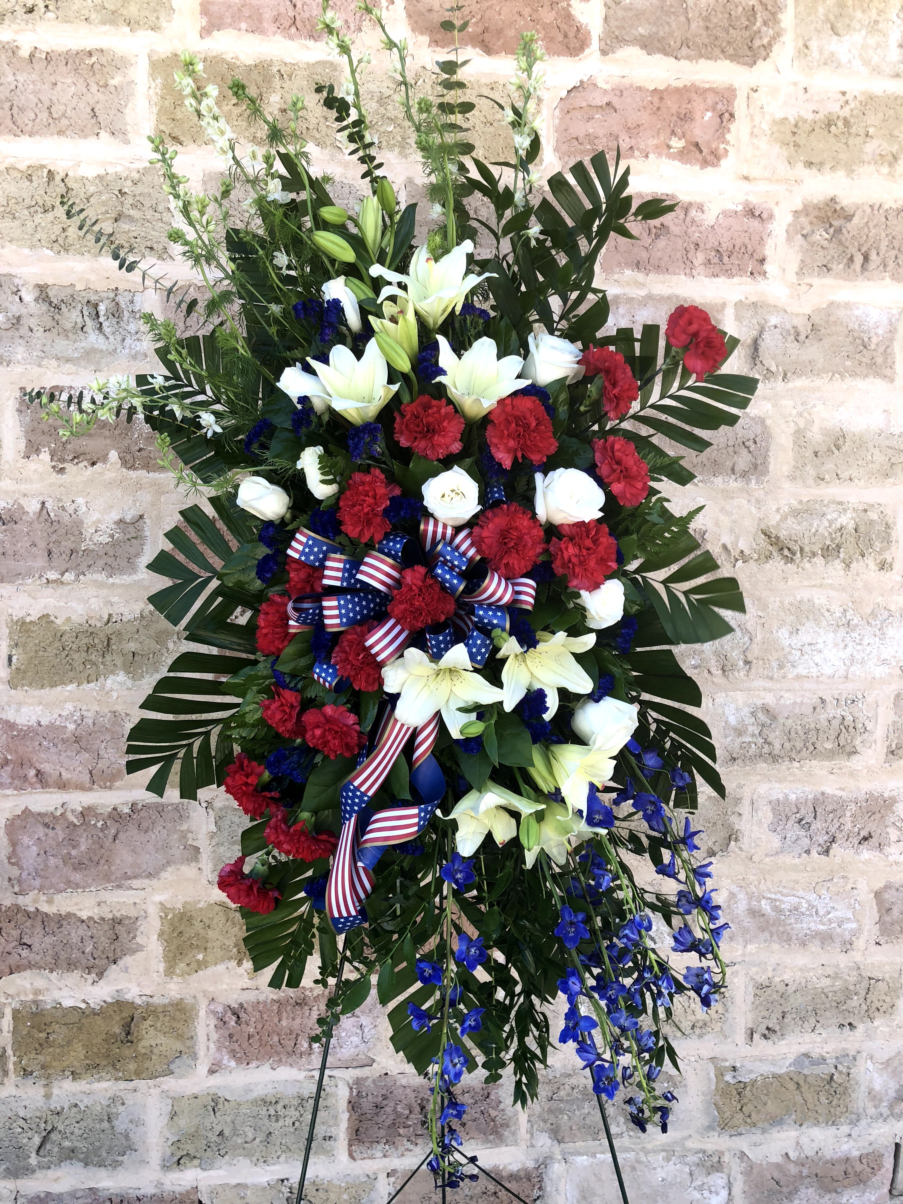 Standing floral spray with red, white, and blue flowers and ribbon