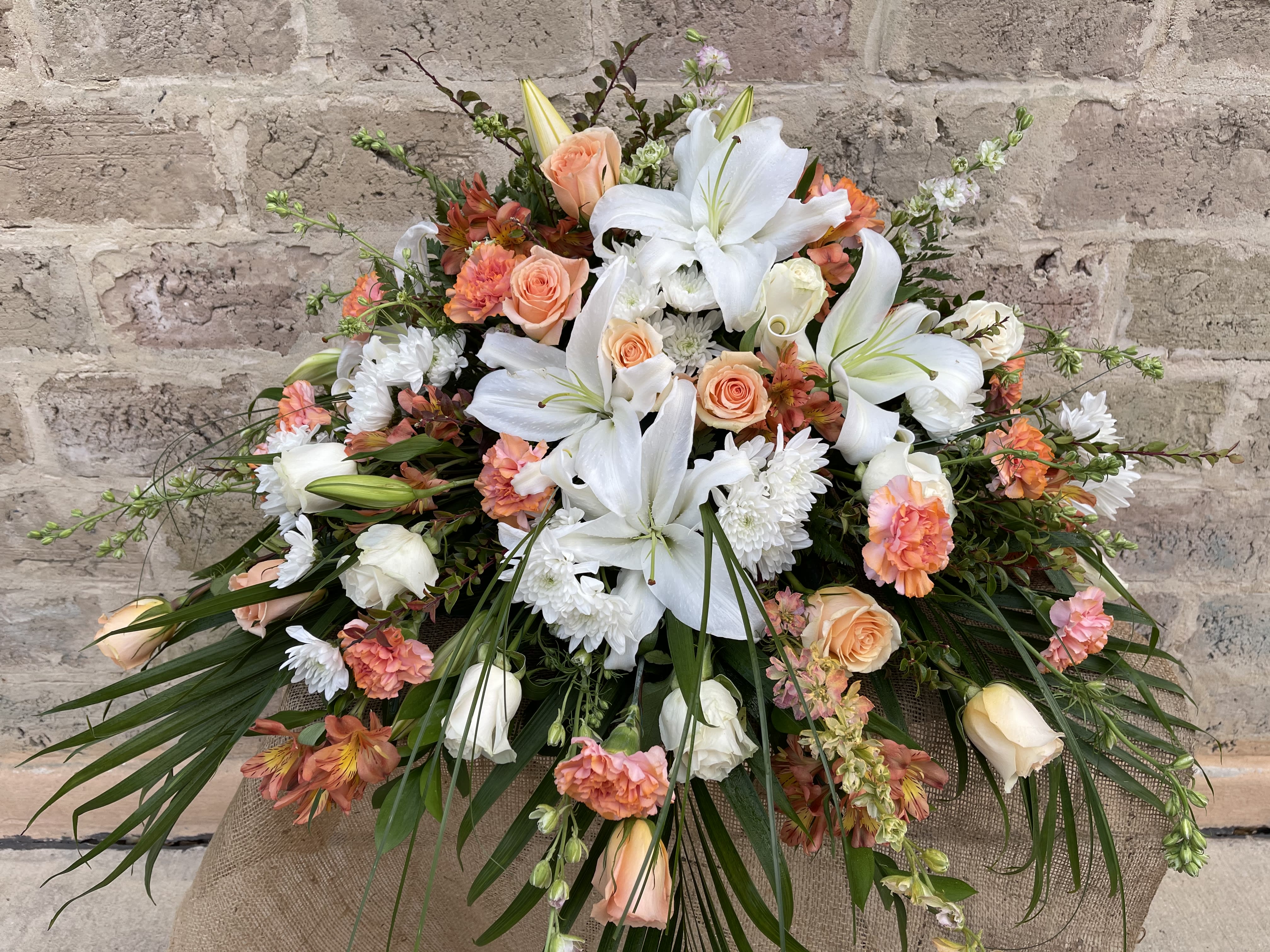 Large bouquet of white lilies, peach roses, and orange carnations
