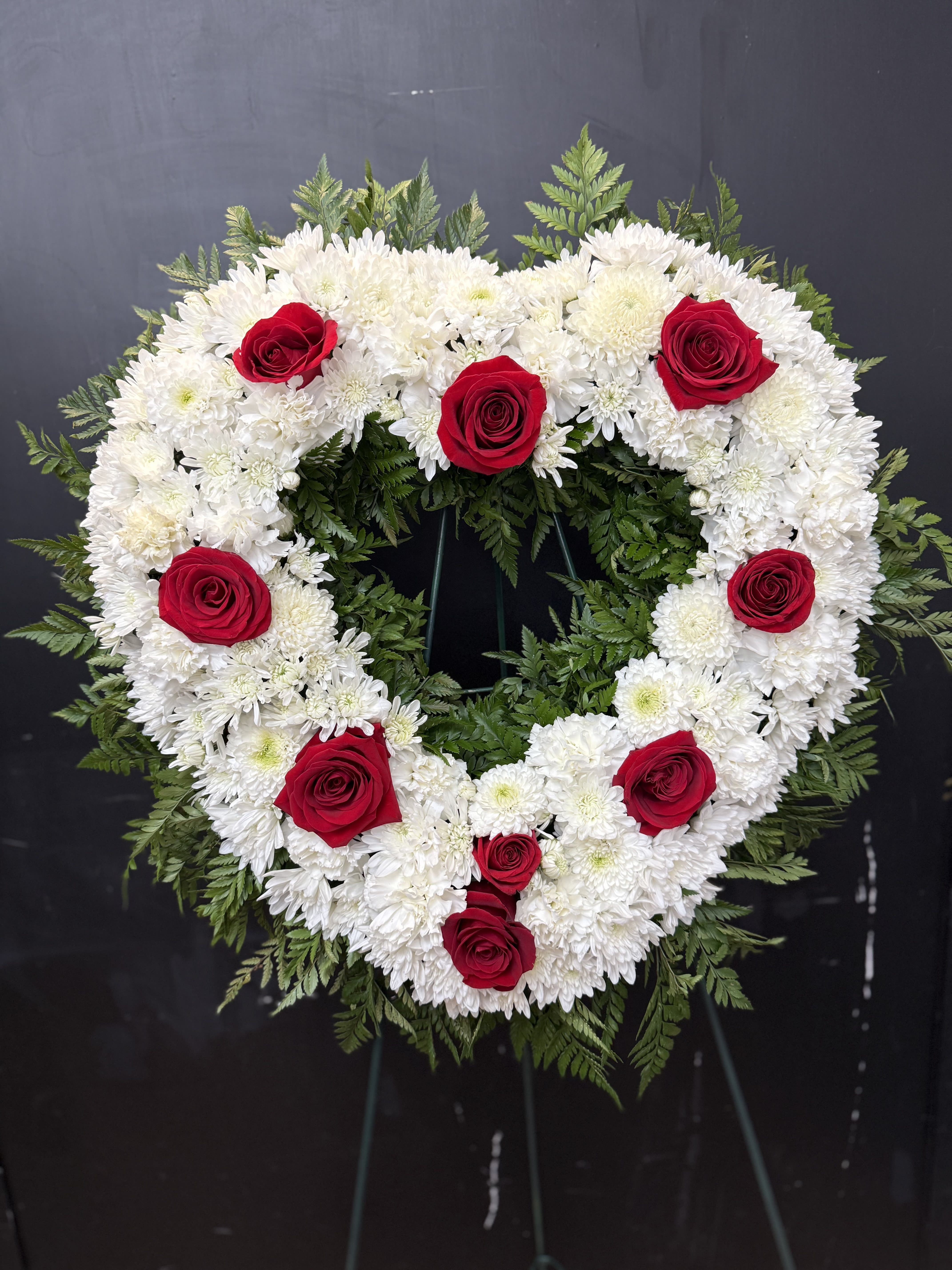 Heart-shaped floral wreath of white flowers with red roses