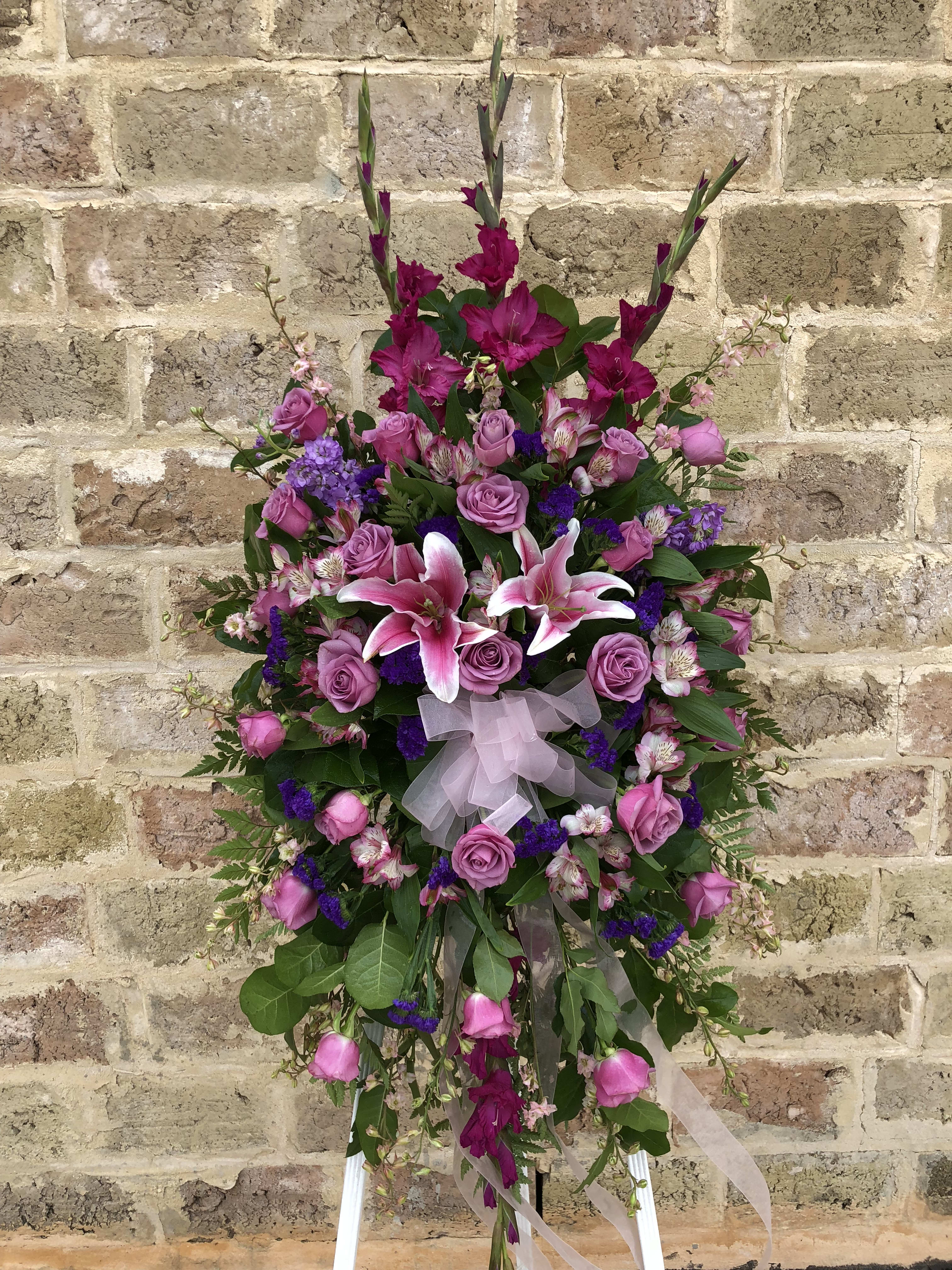Standing floral spray with pink roses and lilies on a white easel