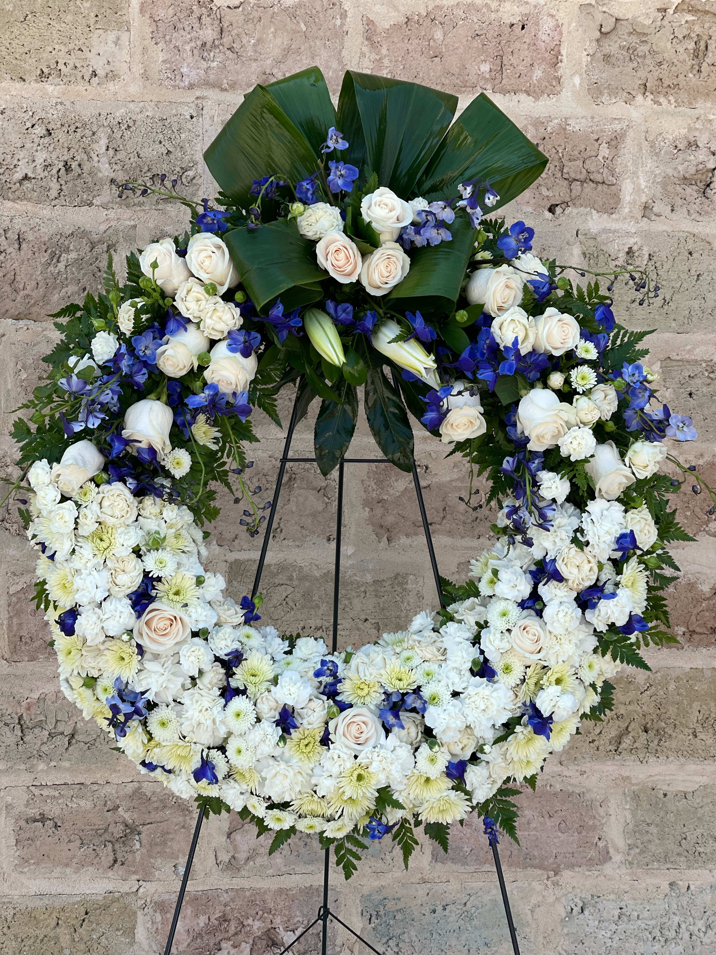 Large white and blue floral wreath on a stand