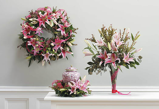 Pink lily arrangements with a matching wreath and vase centerpiece