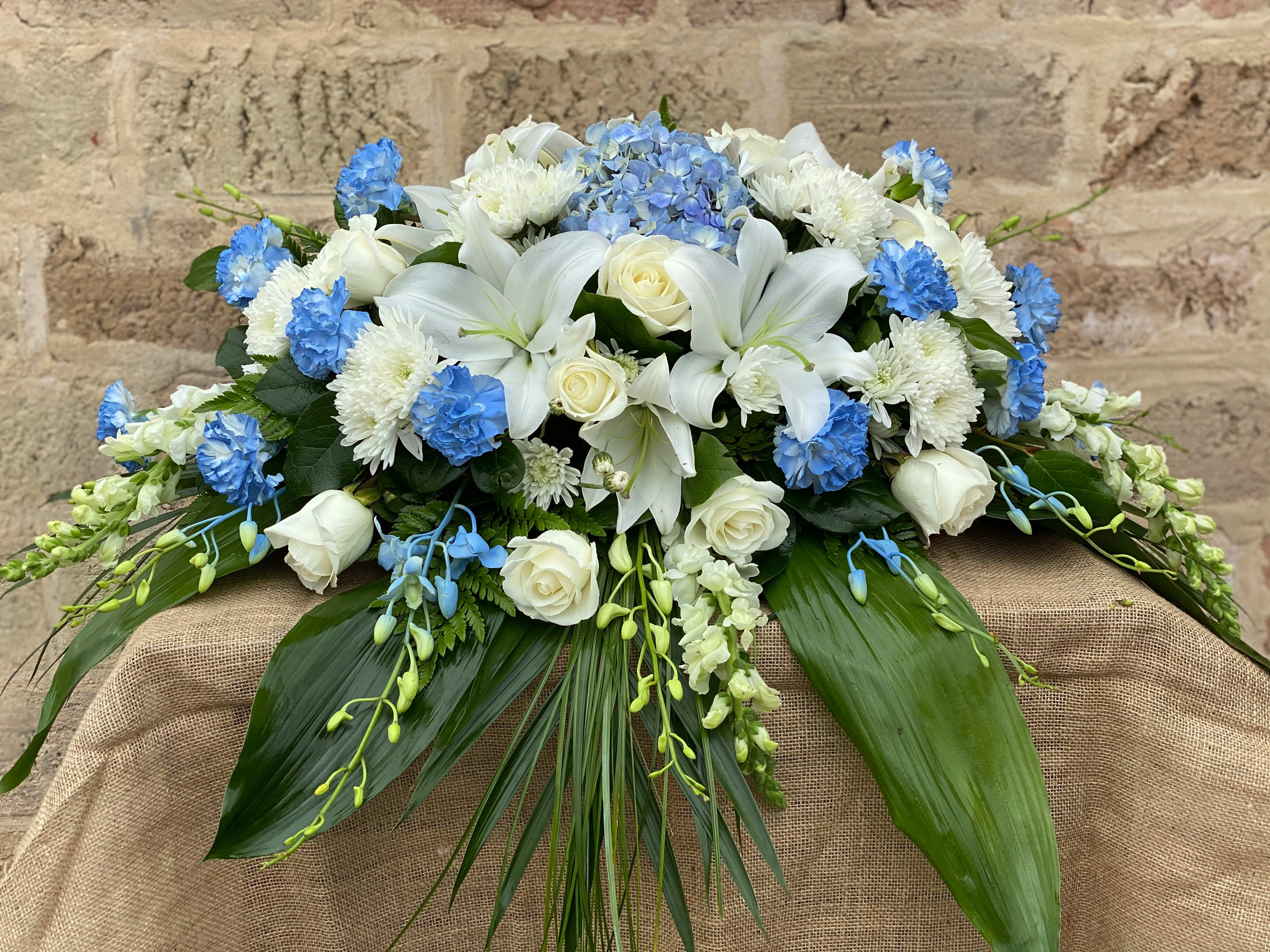 White lilies and roses with blue flowers in a low arrangement