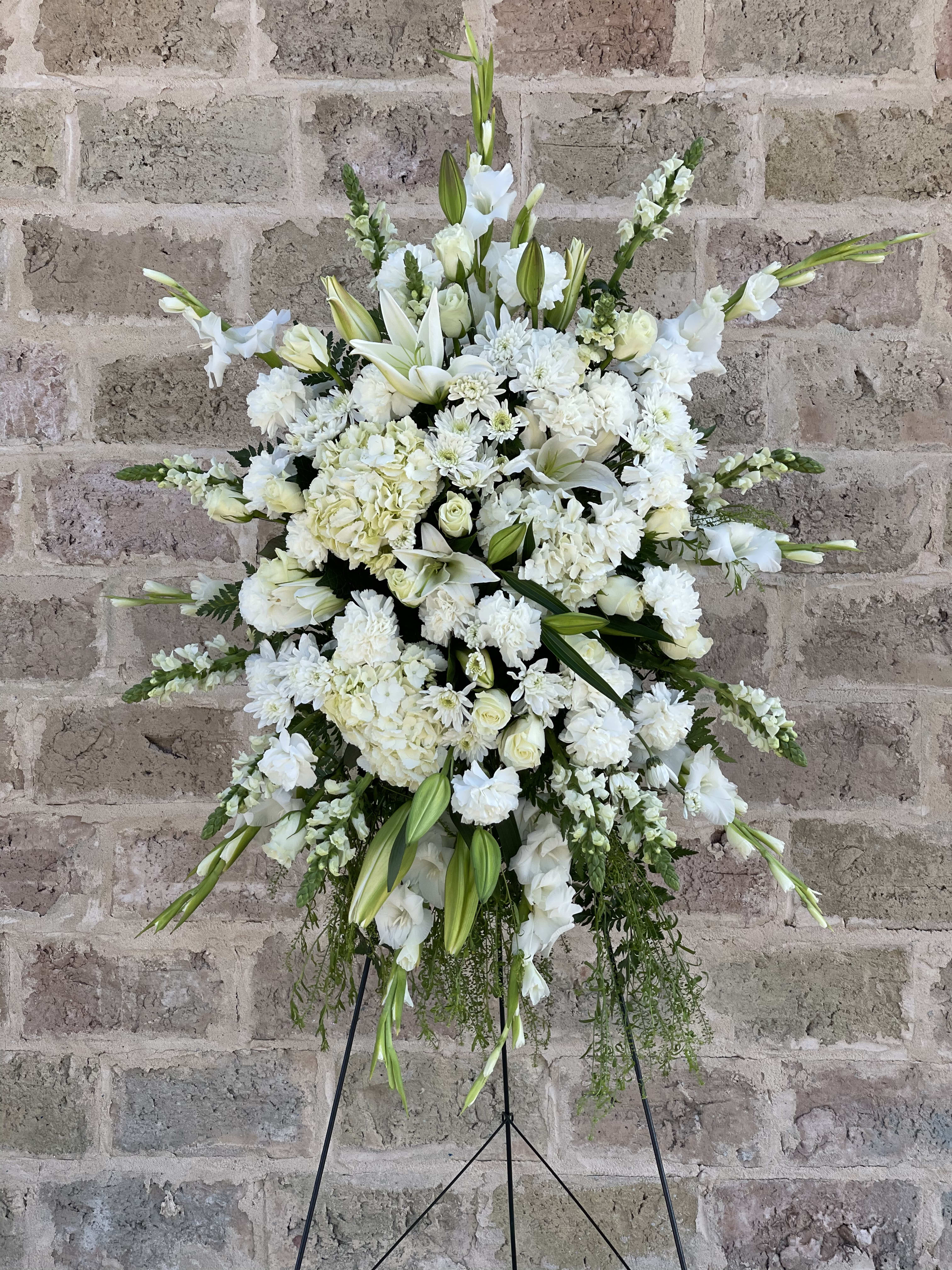 Large white funeral spray with lilies and roses on a stand