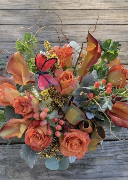 DESIGNERS CHOICE-Rustic - Peach and coral paired with orange-and-cream blossoms create a warm, rustic garden-style bouquet perfect for a  celebration or a cheerful birthday arrangement. This flower arrangement for a celebratory gift feels lively and romantic-the recipient will love! The blue-green foliage, airy twigs, and a bright decorative butterfly that give the design a slightly whimsical, hand-gathered look.  The mixed-color palette of orange, pink, and green seasonal blooms chosen by our designer for texture and movement. Small berry-like accents and loose, natural foliage add depth while keeping the silhouette relaxed rather than formal. A decorative butterfly and twig elements finish the piece, lending an organic, rustic charm.  Made from fresh, seasonal flowers, this designer's choice arrangement is assembled to capture the look shown in the photo as inspiration. It's a thoughtful way to say congratulations, happy birthday, or "I'm thinking of you"-and because it's built from whatever is freshest, slight variations in flower varieties or placement only enhance its hand-crafted appearance.