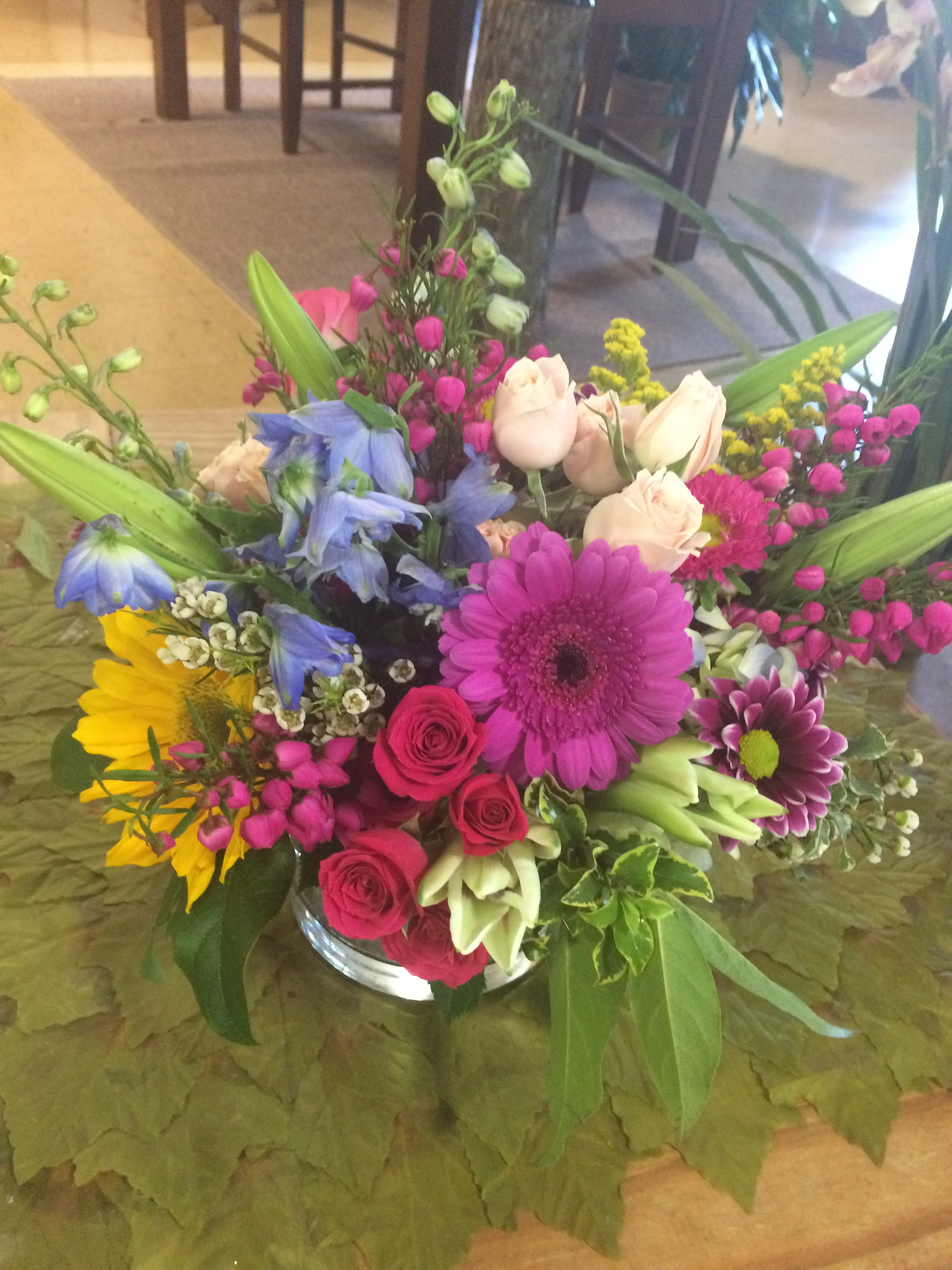 Mixed bouquet in a glass vase with pink, blue, yellow, and white flowers