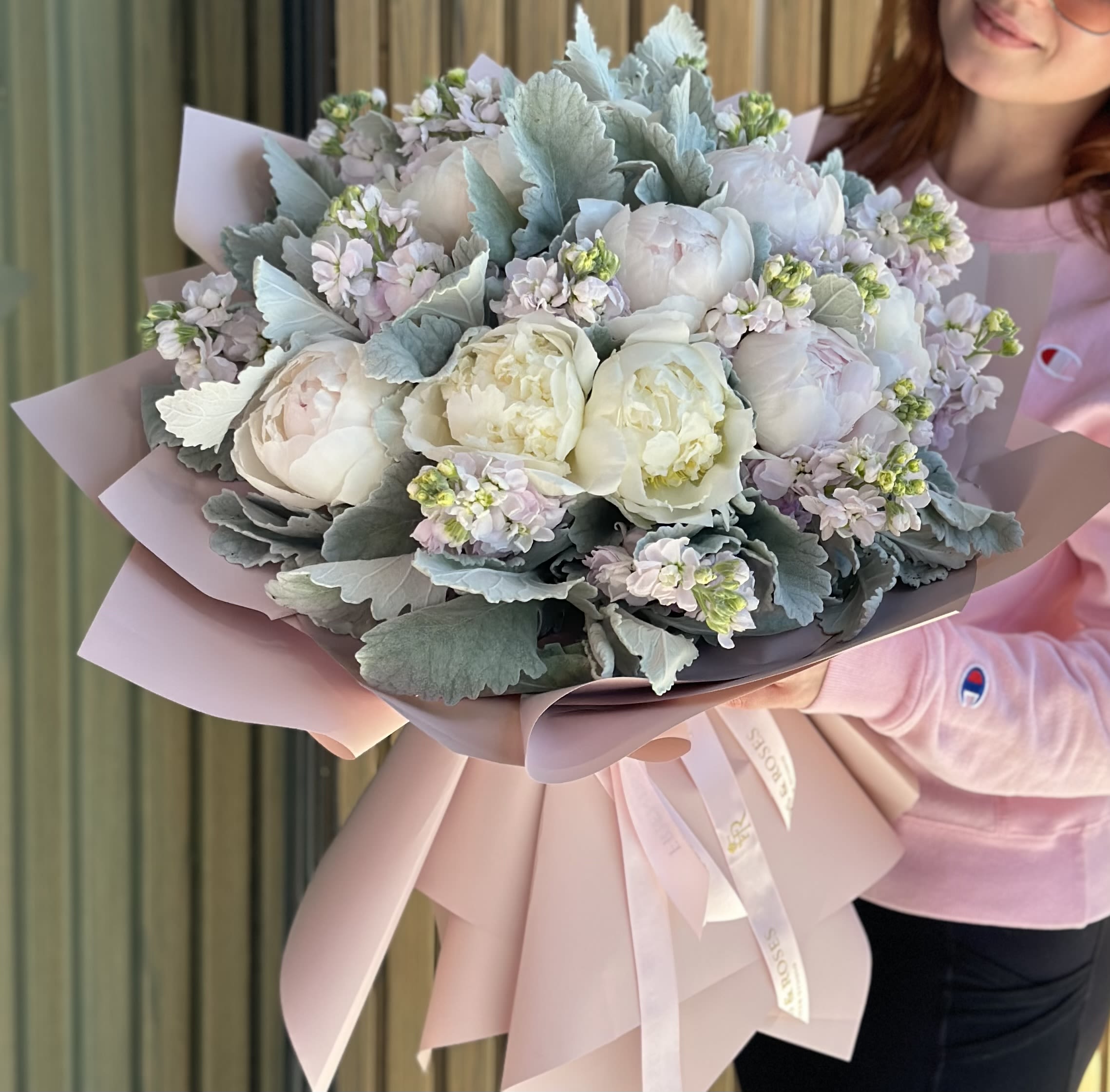 Marshmallow  MD - A hand-tied bouquet with pastel peonies features full, delicate blooms arranged in a soft, natural style. The pastel colors add a gentle, romantic touch, while airy greenery enhances the bouquet’s light, elegant feel. Wrapped in paper and ribbon, it has a fresh, effortless charm.