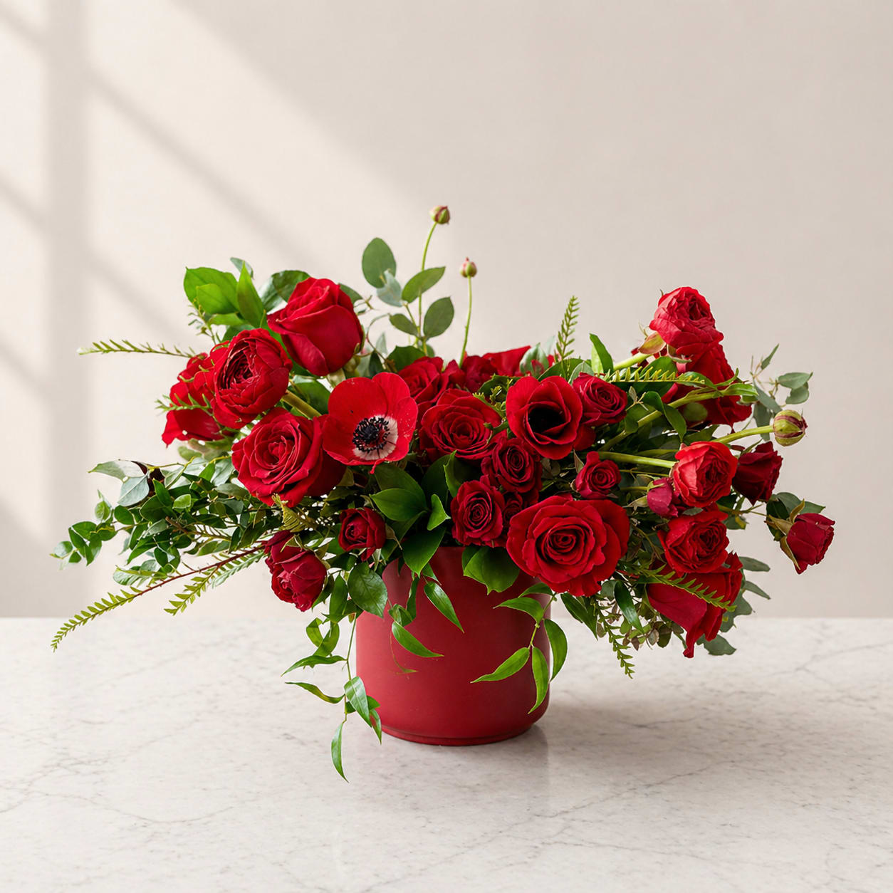 Anita - Our Anita arrangement is an all red flower arrangement filled with Red roses, red spray roses, Anemone, Ranunculus and greenery for added textures in a ceramic red vase. The Anita is the perfect arrangement for any occasion to bring a smile to your loved one.  