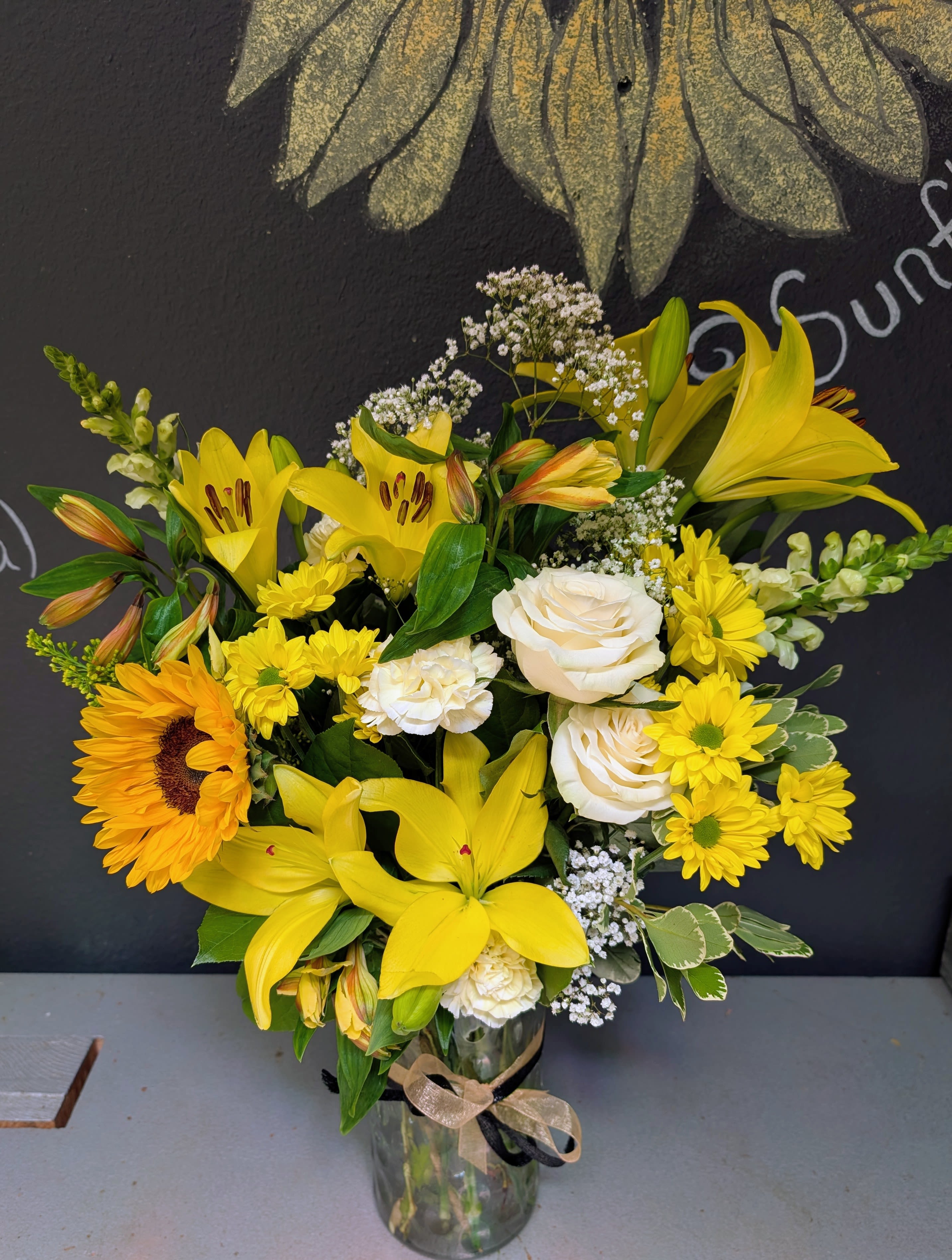 CU Boulder *Graduation Special* - Vased - Celebrate your CU Boulder graduate in style with opulent vased arrangement in classic whites and yellows, accented by elegant gold and black ribbons—perfectly reflecting school pride and achievement. This beautifully arranged piece adds a bright, sophisticated touch to their big day, making it a meaningful gift they’ll remember long after the celebration ends. Whether for photos, parties, or a heartfelt surprise, it’s a simple way to honor all their hard work and success.